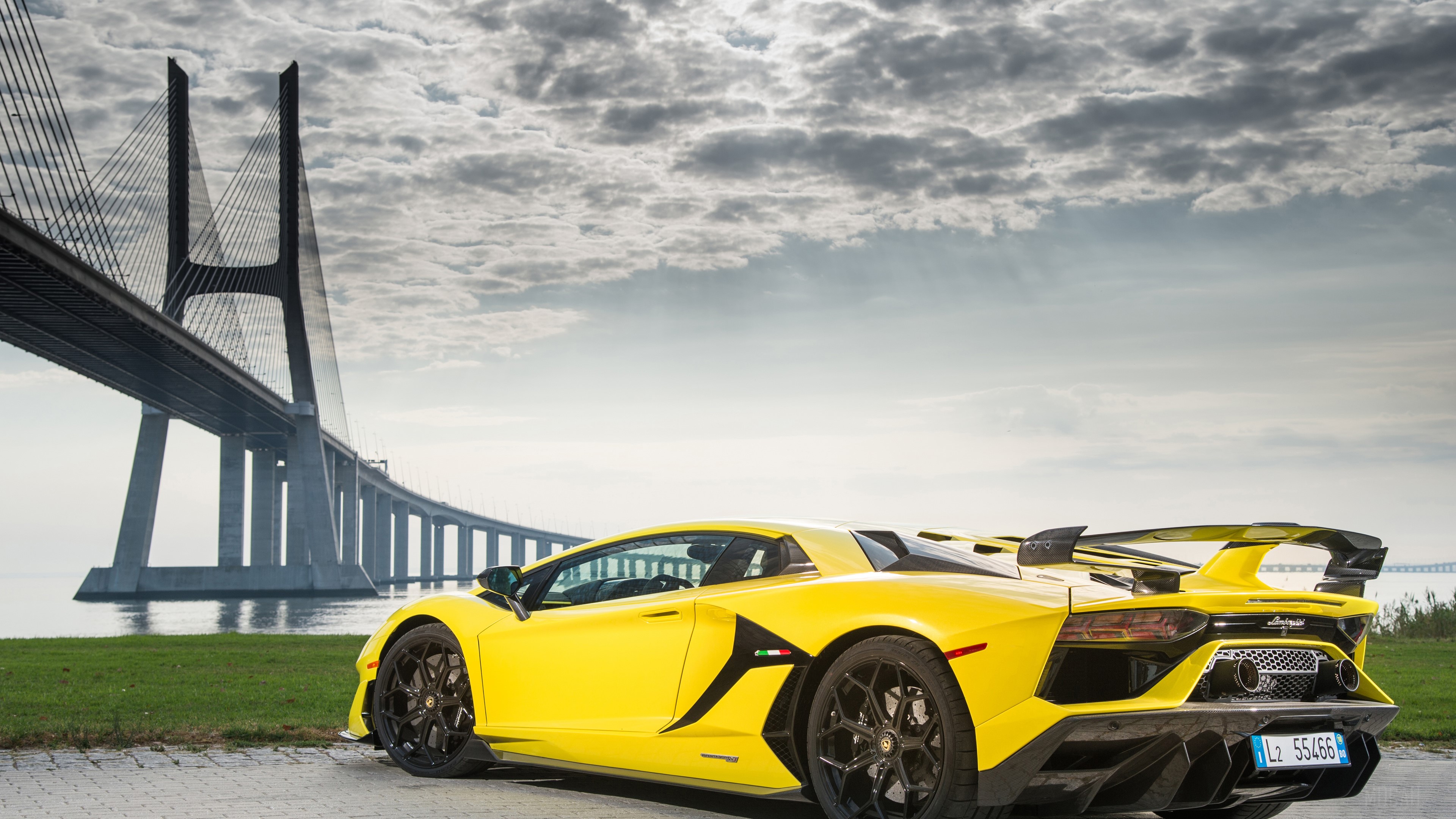 Yellow 2019 Lamborghini Aventador SVJ near Vasco da Gama Bridge HD Wallpaper
