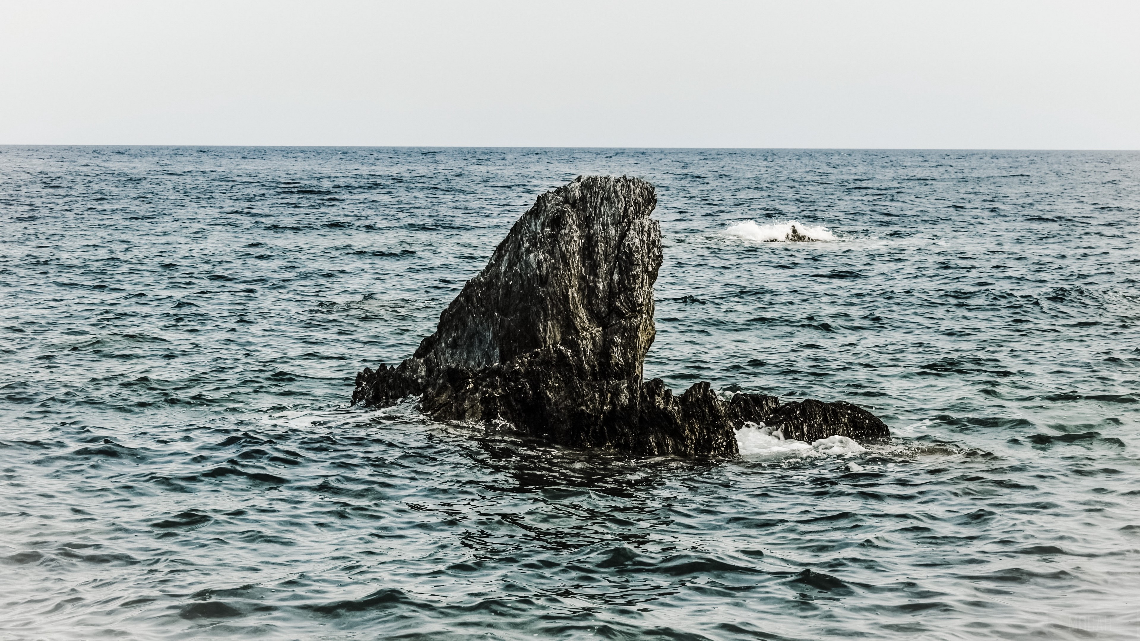 Rock formation in the sea under a pale sky HD Wallpaper