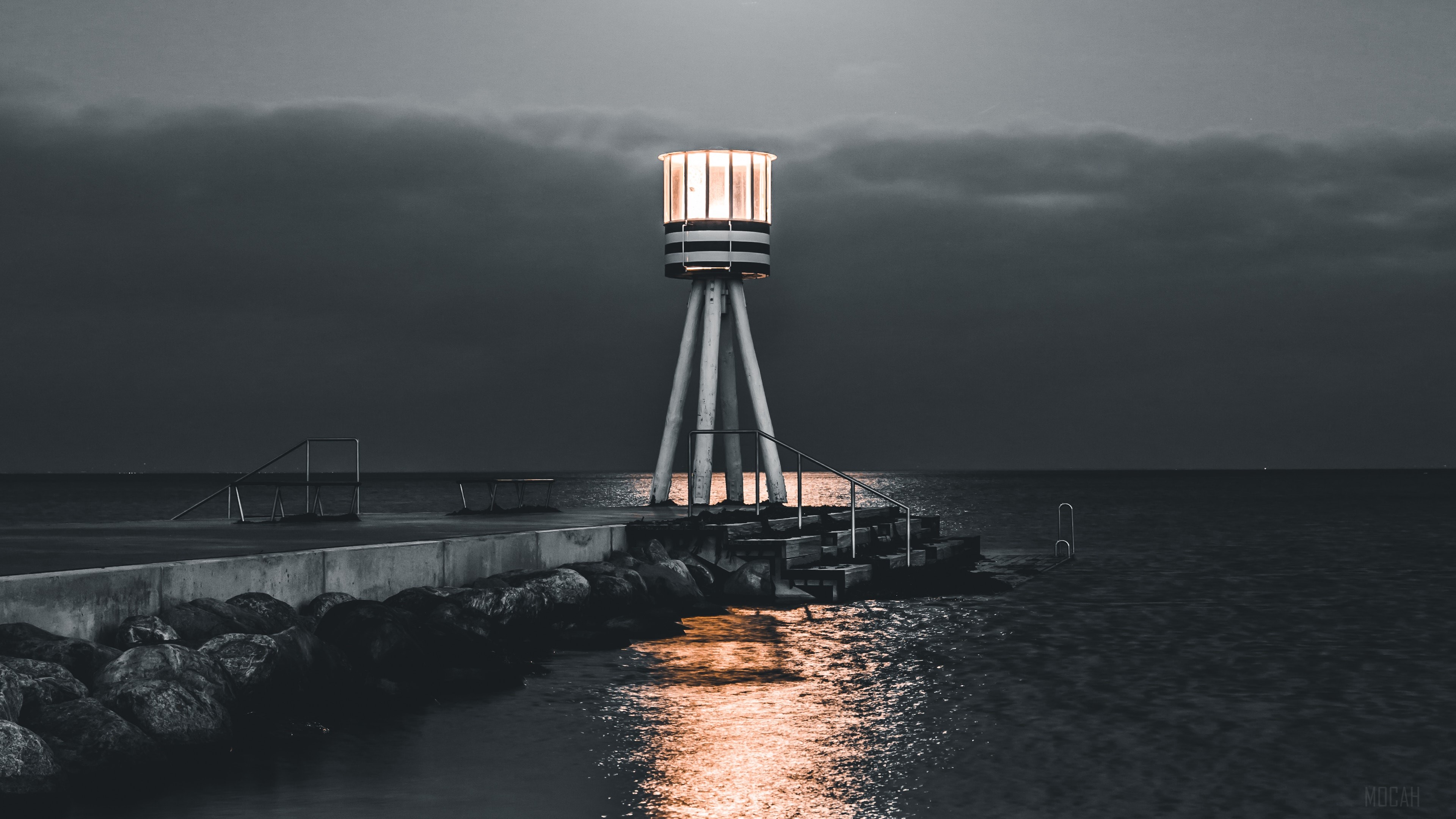 Lighthouse on a pier at night with sea and stones 4K HD Wallpaper