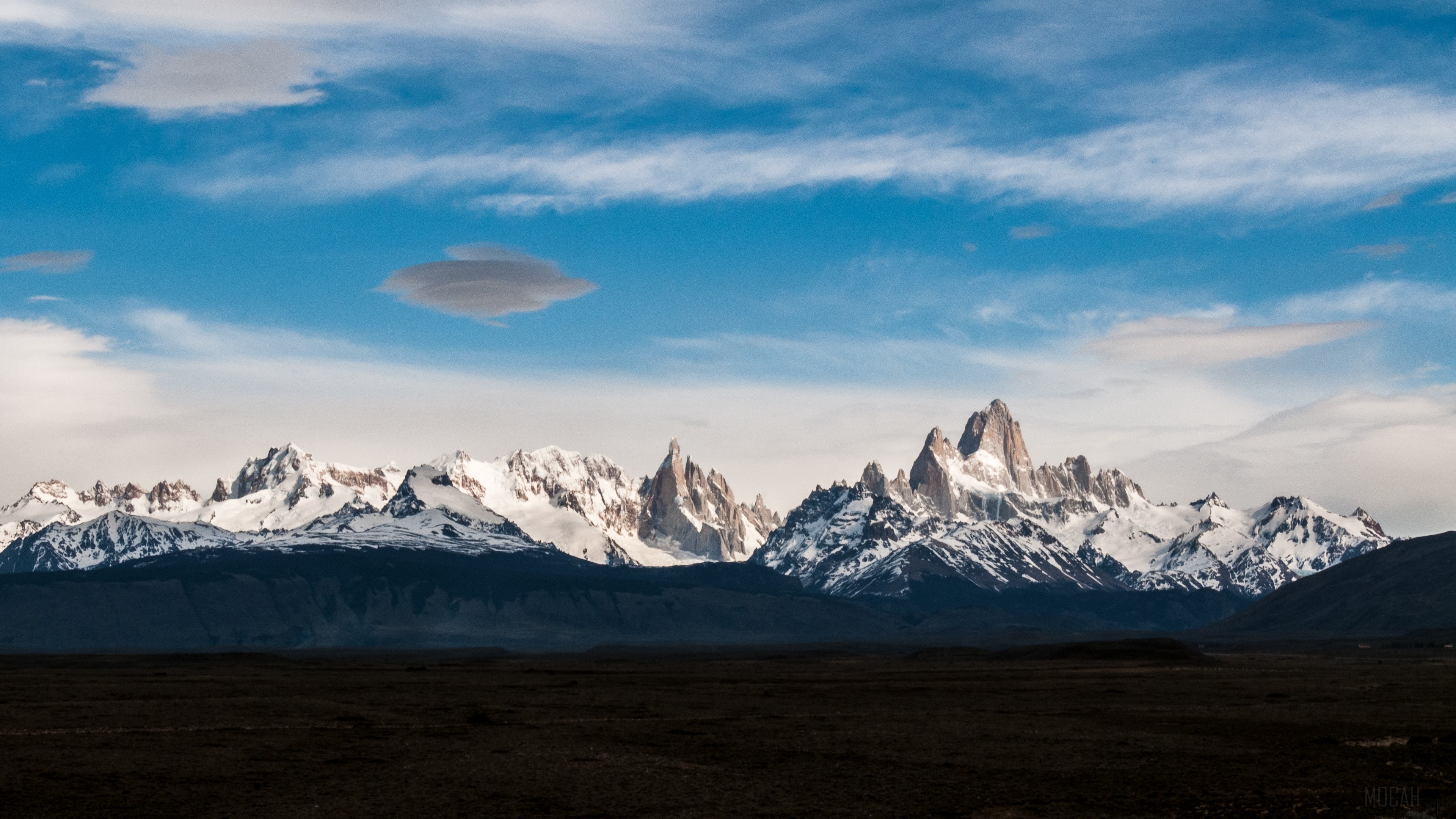 Snow-capped mountains under a cloudy blue sky HD Wallpaper