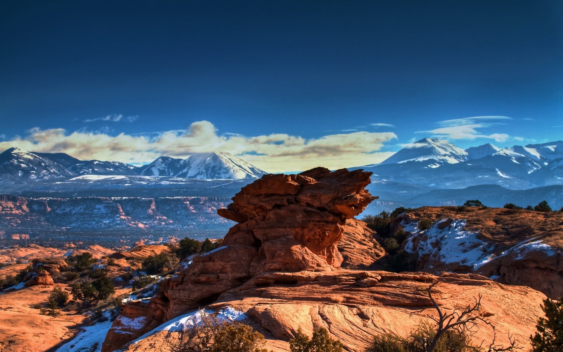 Red rock formations and snow-capped mountains under a blue sky HD Wallpaper