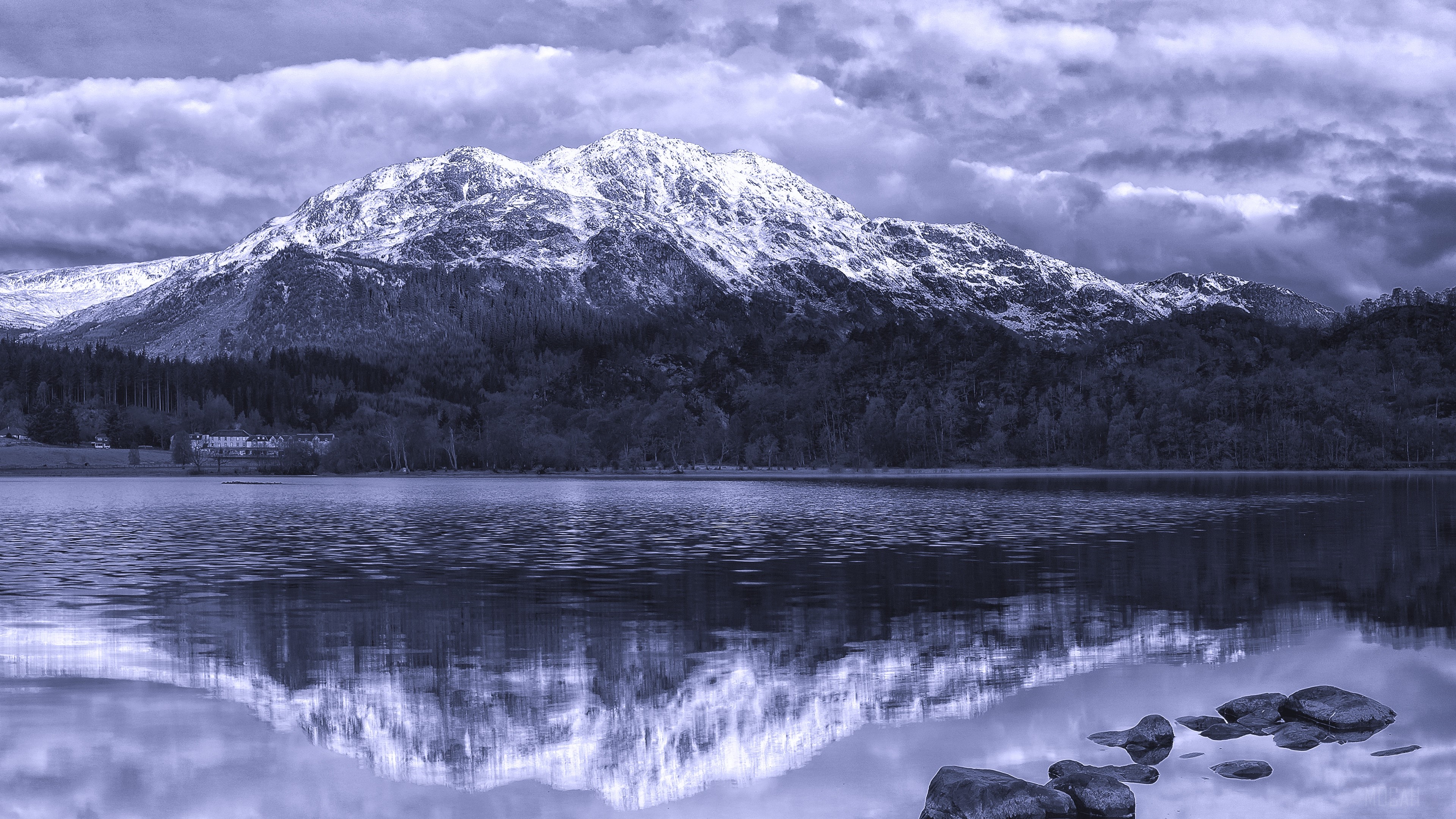 Snow-capped mountains reflected in a lake with stones HD Wallpaper