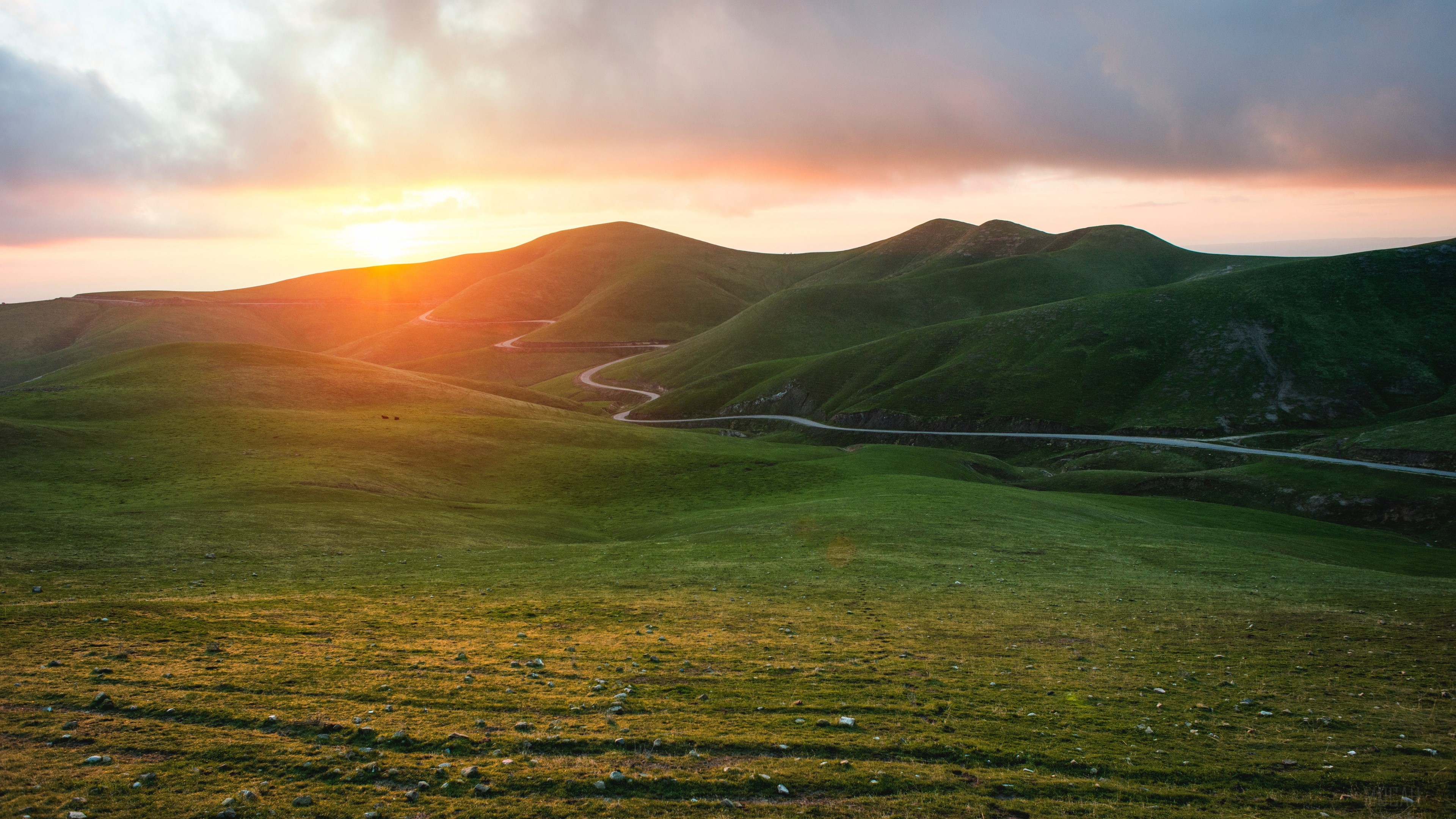 Winding road through green mountains at sunset 4K HD Wallpaper