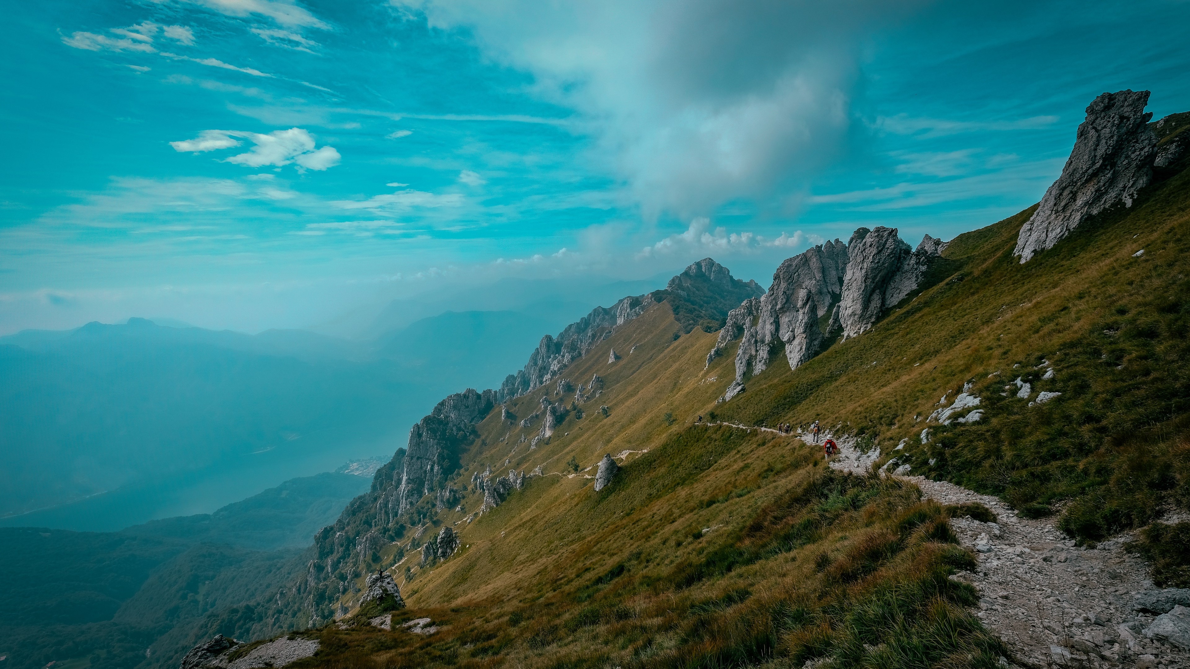 Mountain path with rocks and grass under a blue sky HD Wallpaper