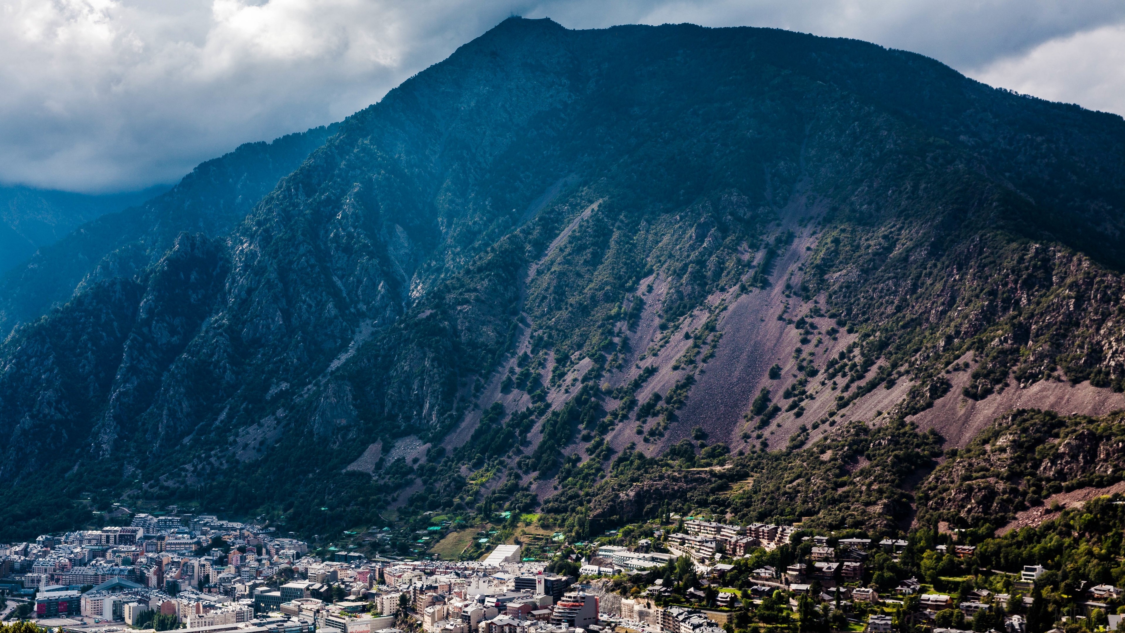City nestled at the base of a large mountain range HD Wallpaper