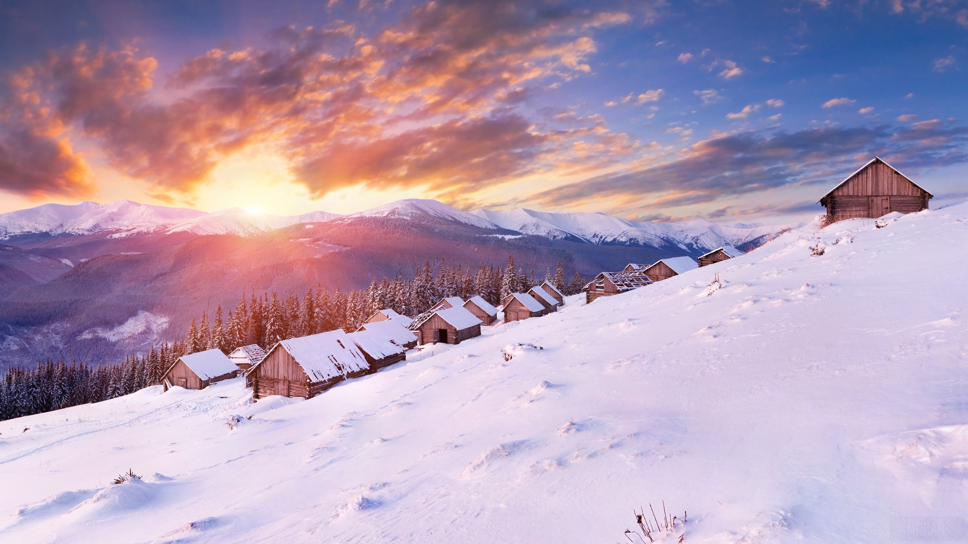 Wooden houses on a snowy mountain slope at sunset 4K HD Wallpaper