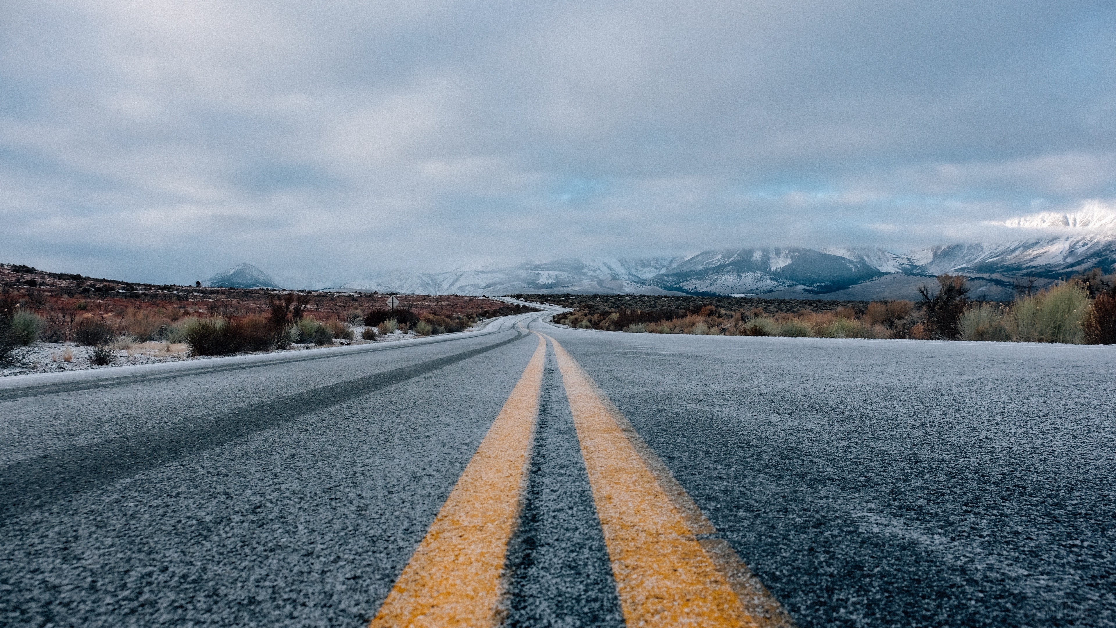 Road with yellow markings and snowy mountains HD Wallpaper