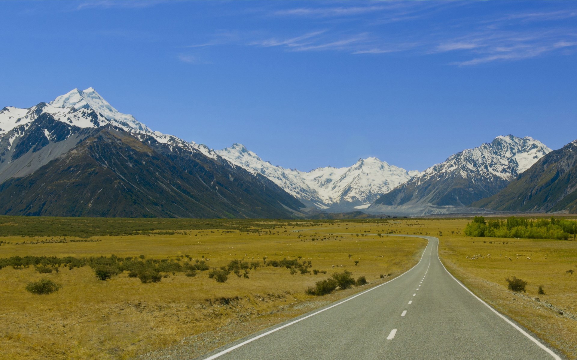 Road leading to snow-capped mountains HD Wallpaper