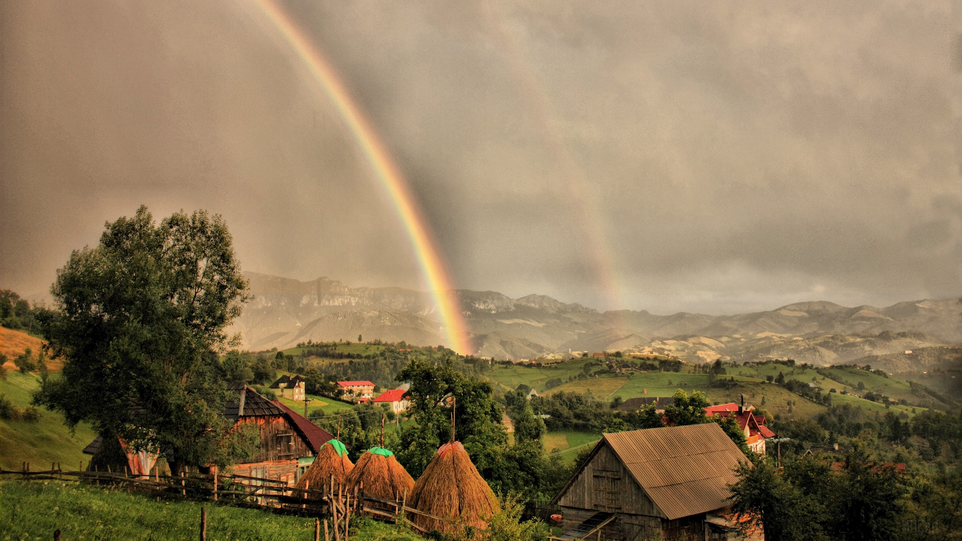 Double rainbow over a rural landscape with houses and haystacks HD Wallpaper