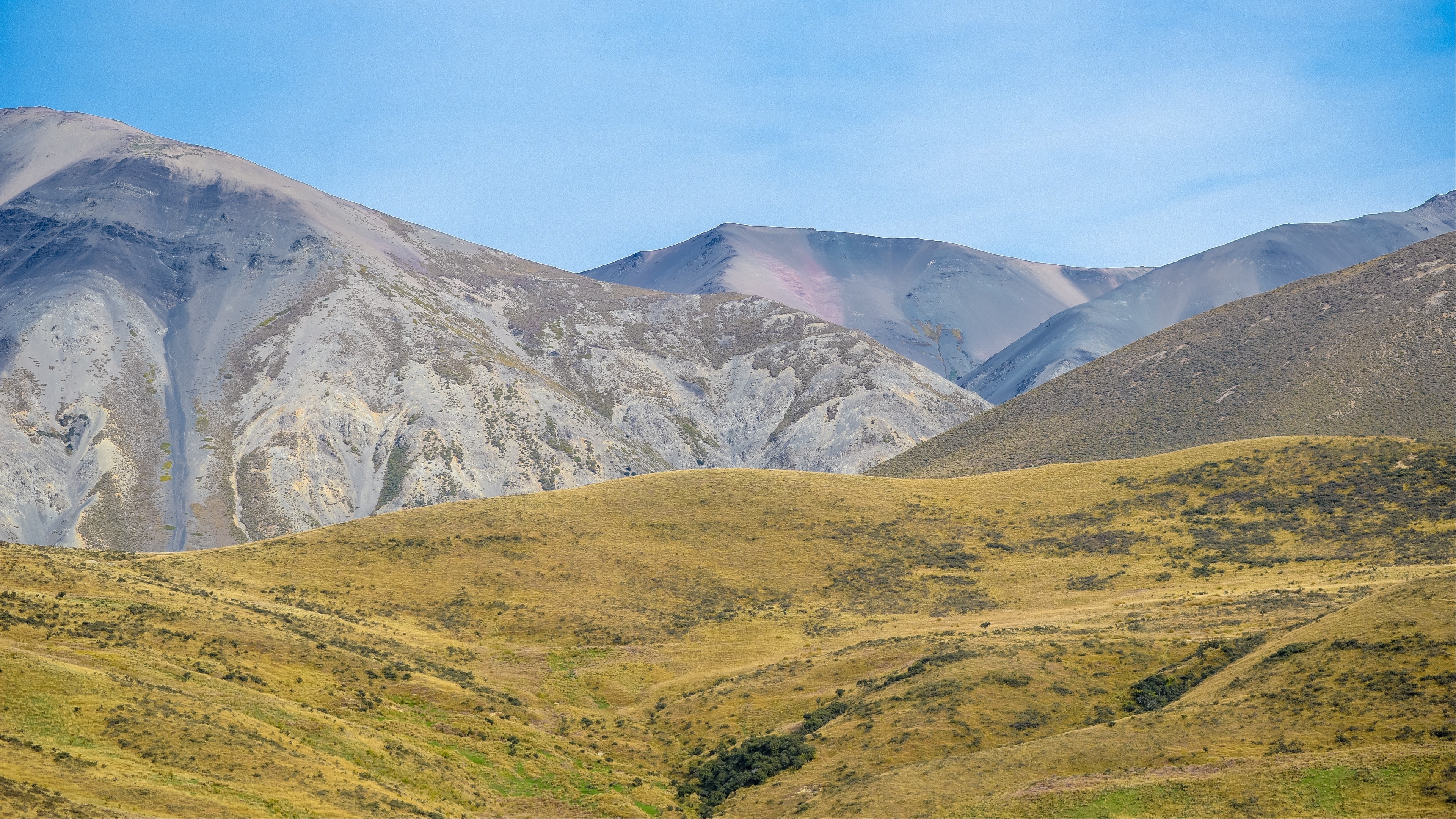 Mountains and grassy hills under a blue sky HD Wallpaper