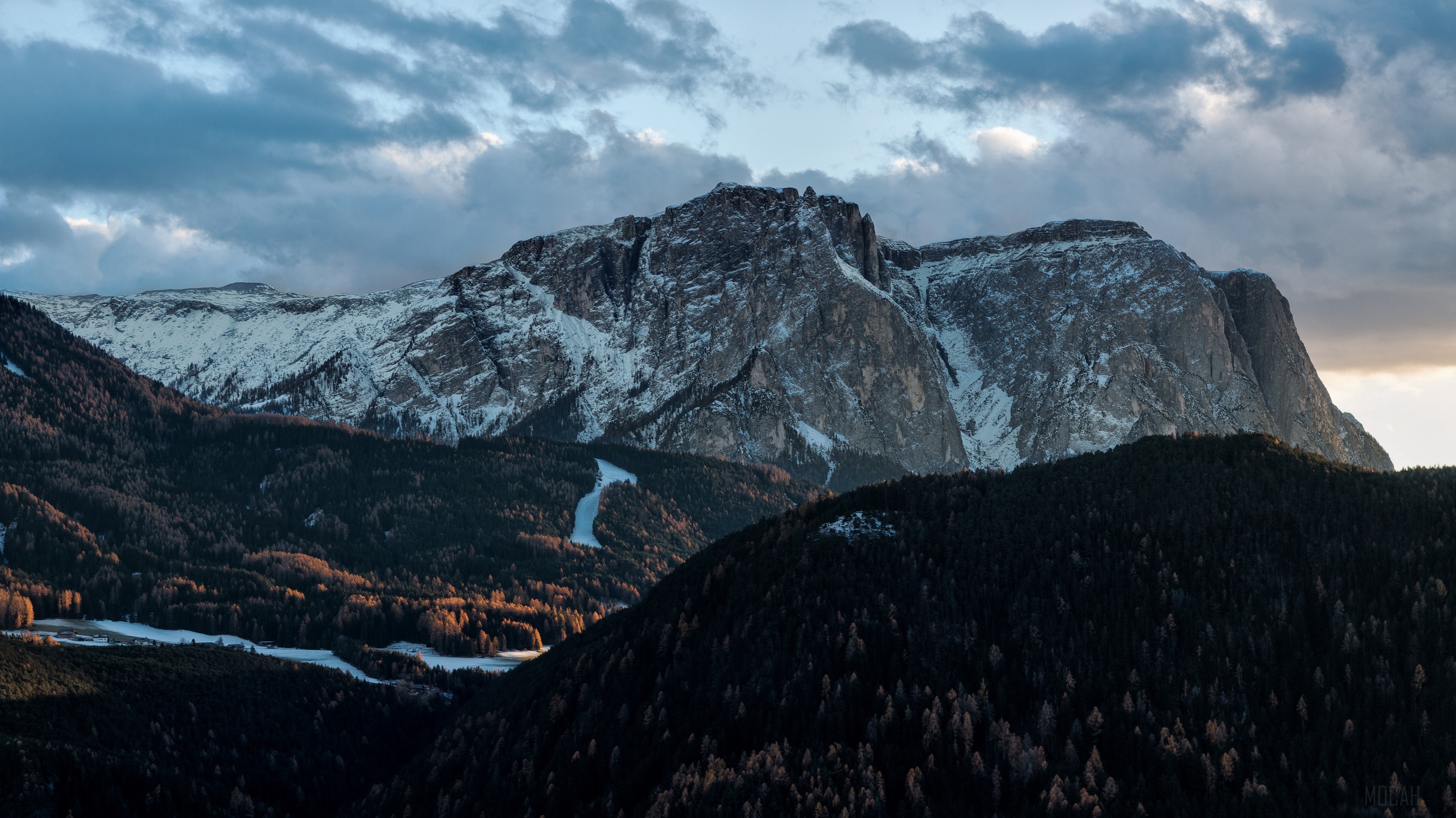 Snow-capped mountains and dark forests under cloudy sky 4K HD Wallpaper