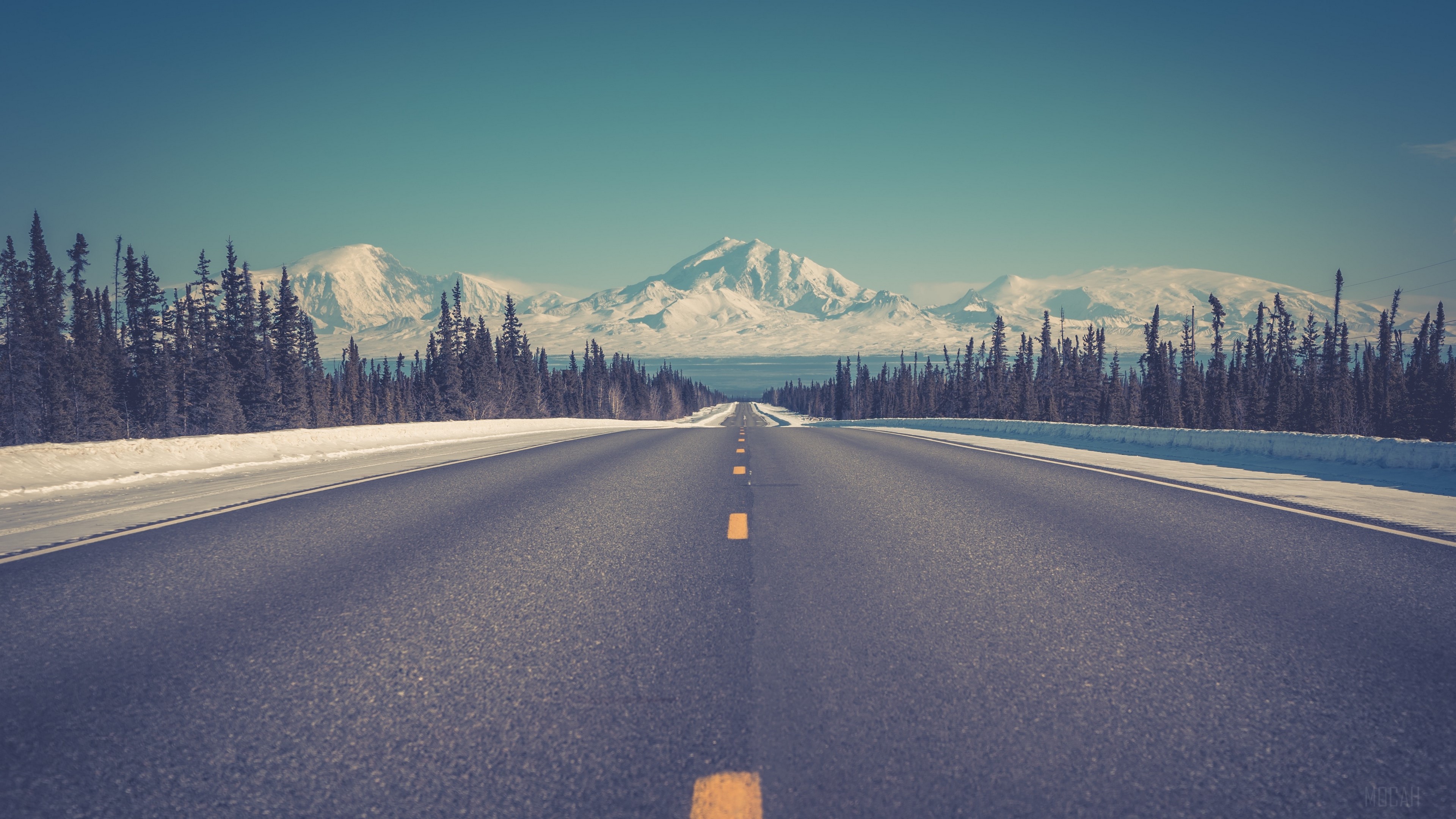 Asphalt road leading to snow-capped mountains HD Wallpaper