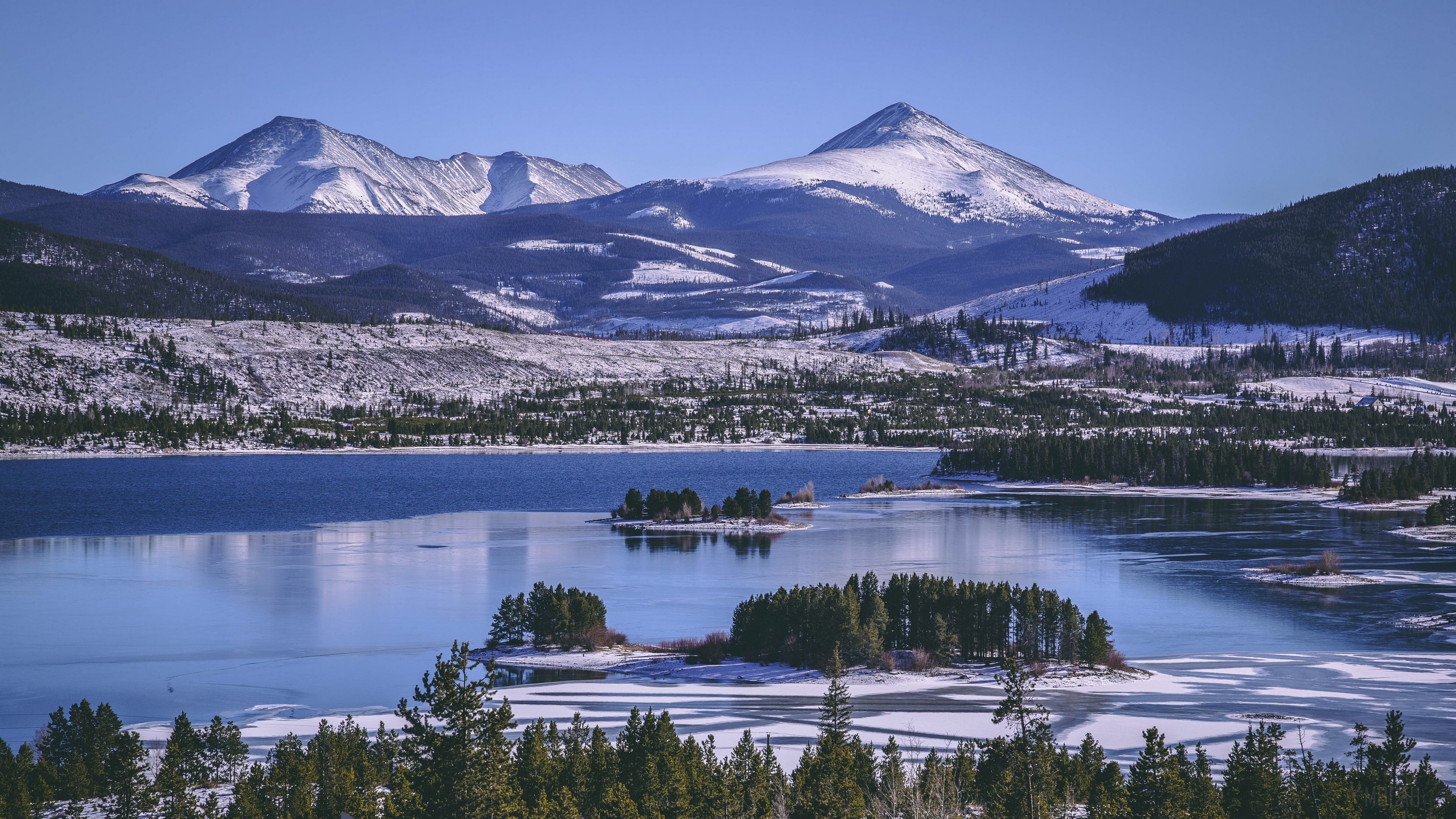 Winter landscape with snow-capped mountains and a partially frozen lake HD Wallpaper