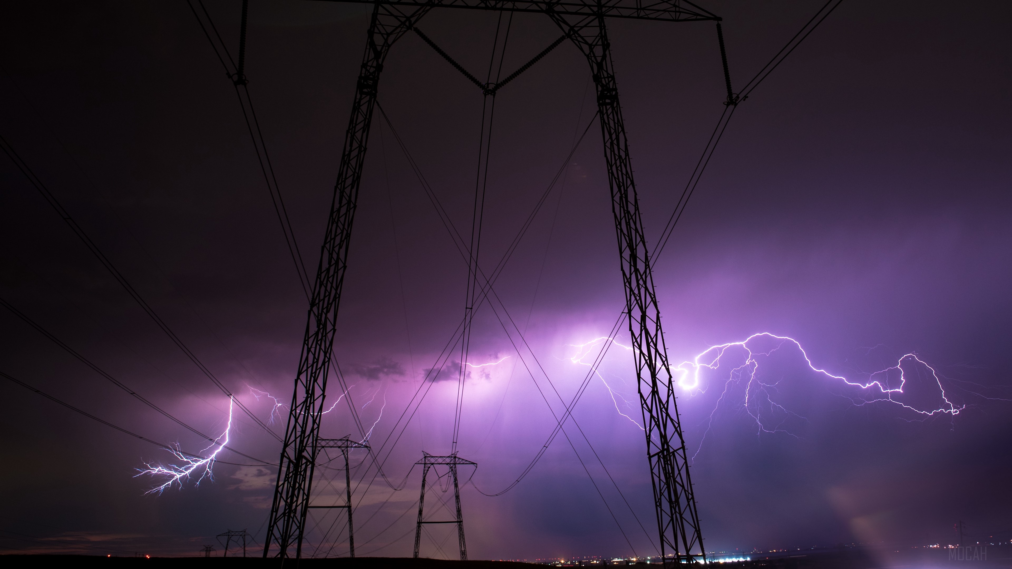 Lightning strikes illuminate the night sky behind power lines HD Wallpaper