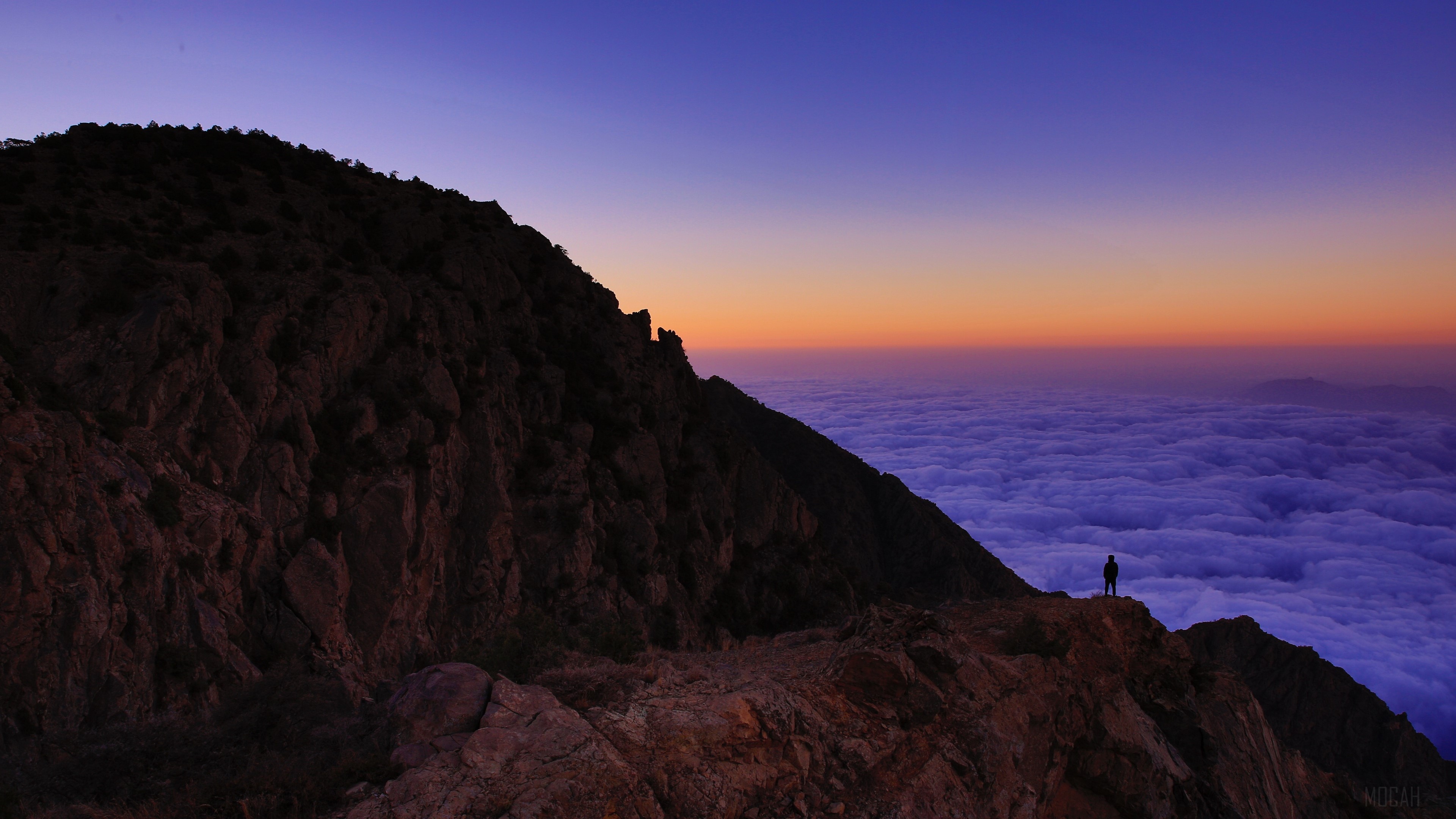 Man standing on mountain peak above clouds at sunset, Al Bahah, Saudi Arabia 4K HD Wallpaper