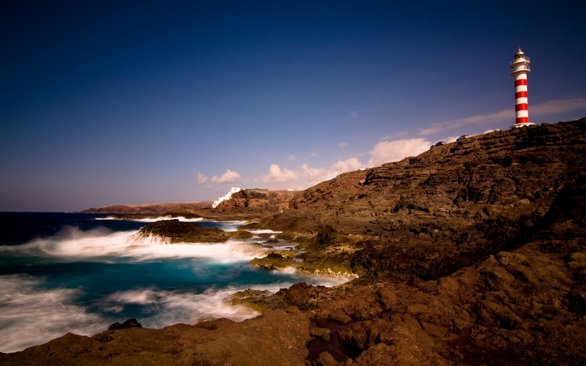 Red and white lighthouse on a rocky coast HD Wallpaper