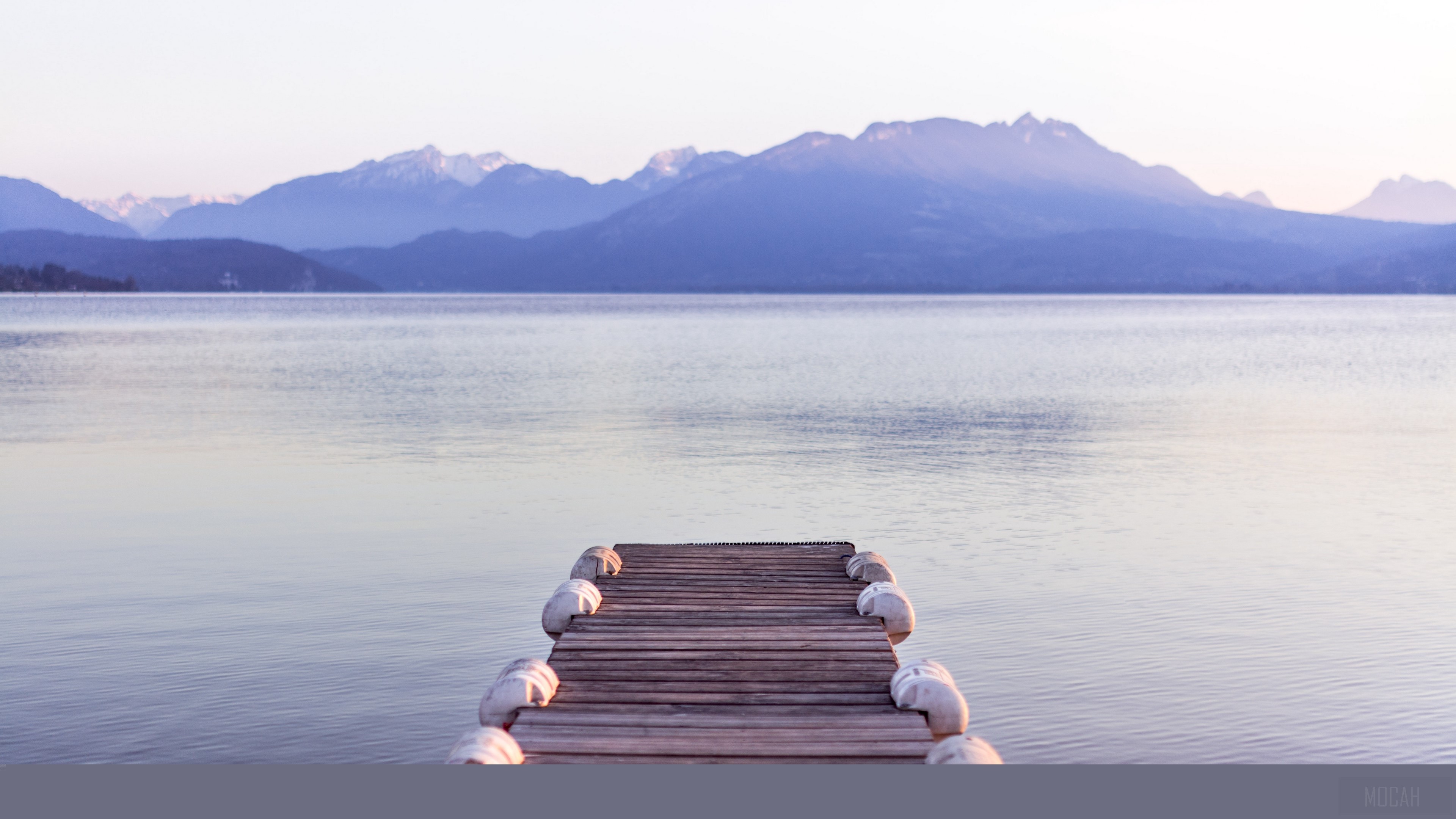 Wooden pier on a lake with mountains in the background 4K HD Wallpaper