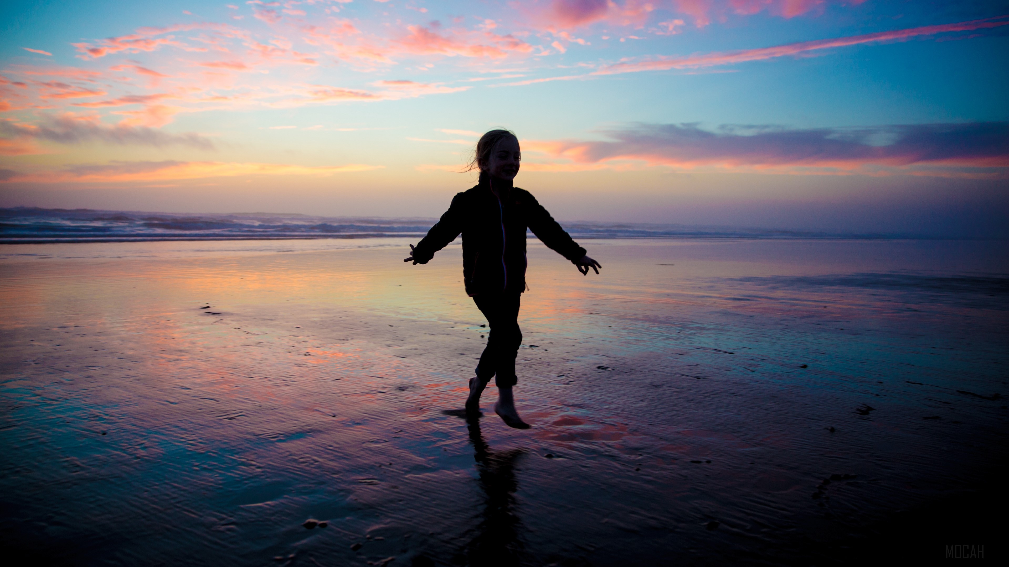 Child jumping on a beach at sunset 4K HD Wallpaper