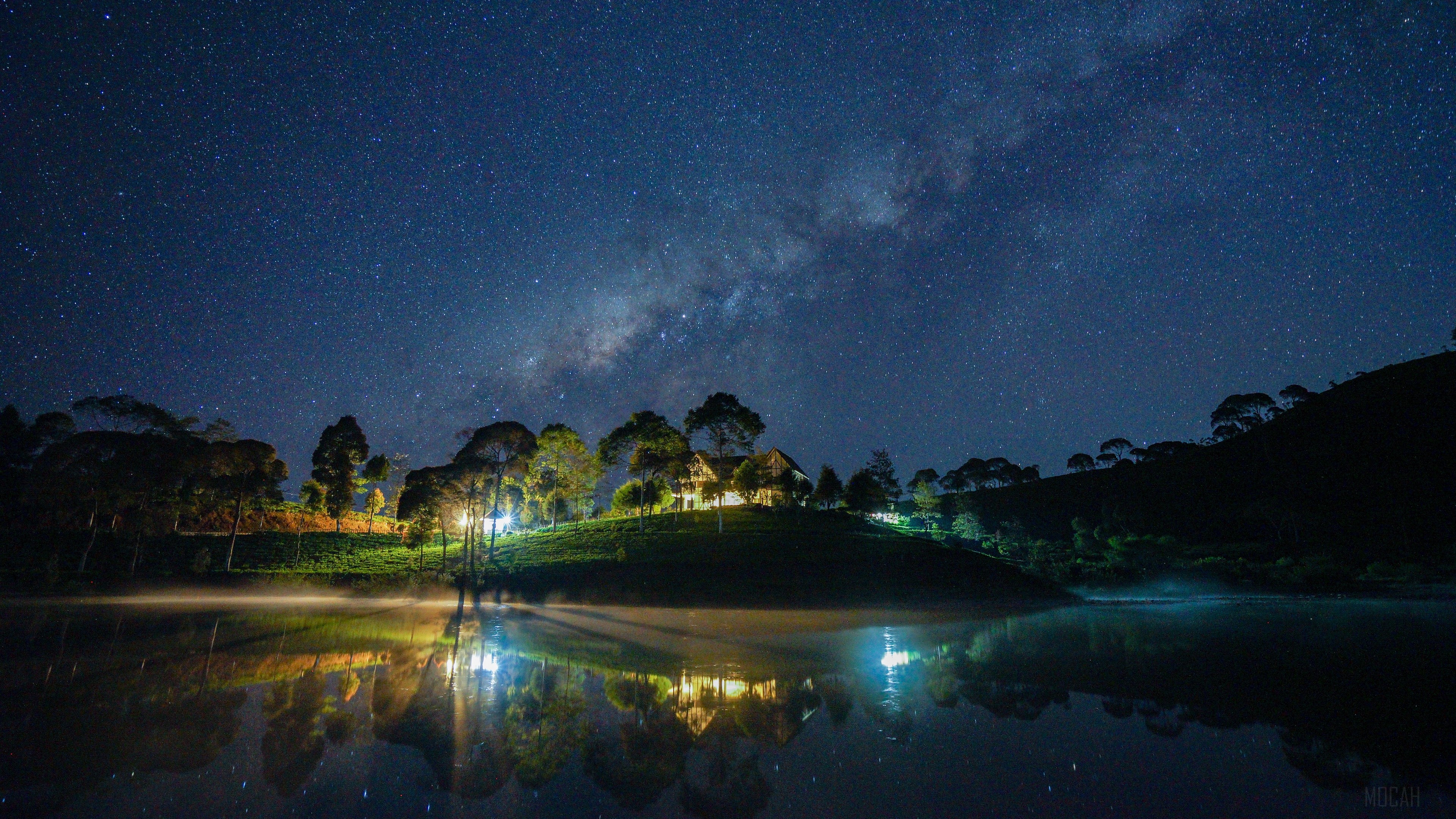 Milky Way over a lake with illuminated houses HD Wallpaper