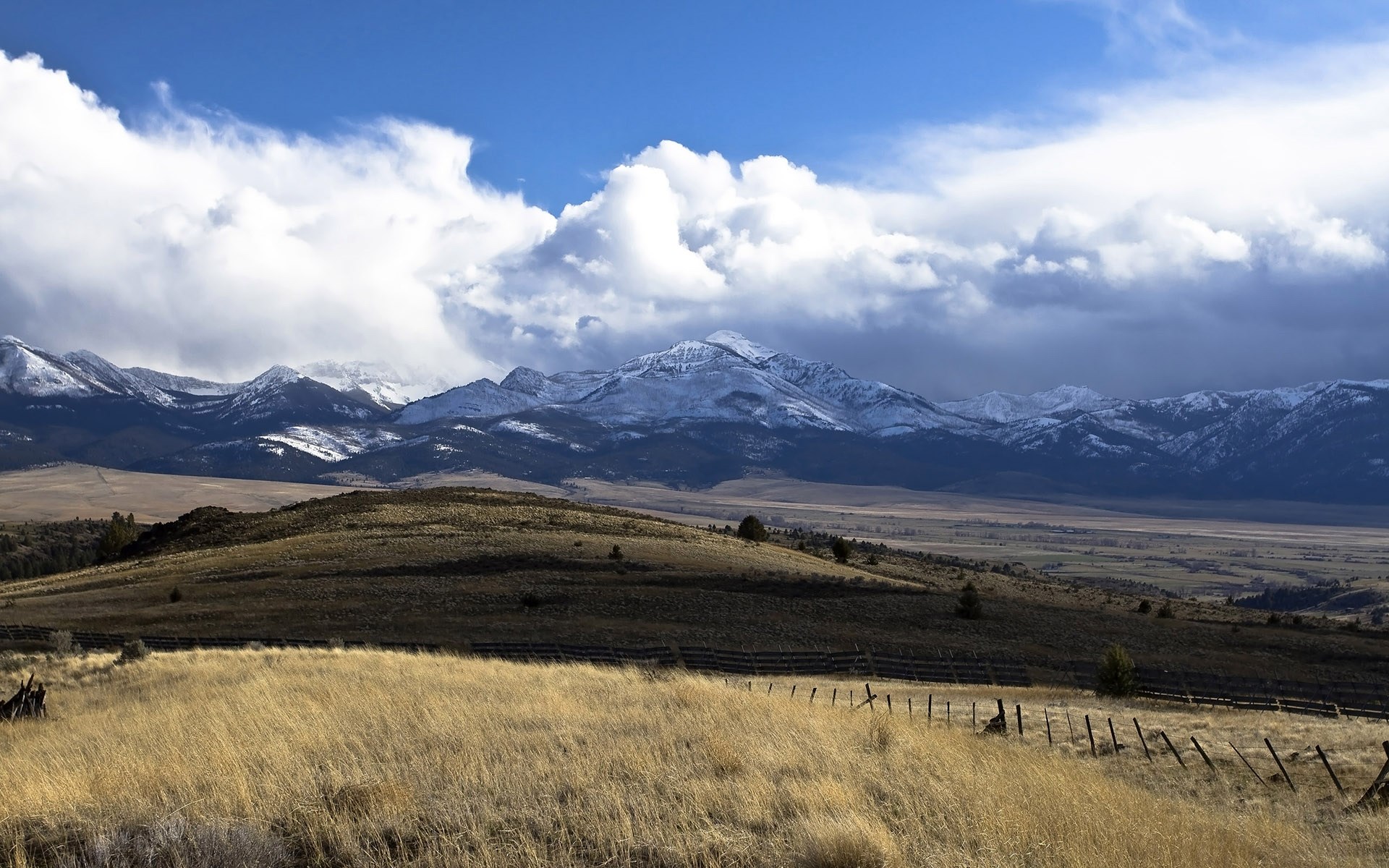 Snow-capped mountains under a cloudy sky HD Wallpaper