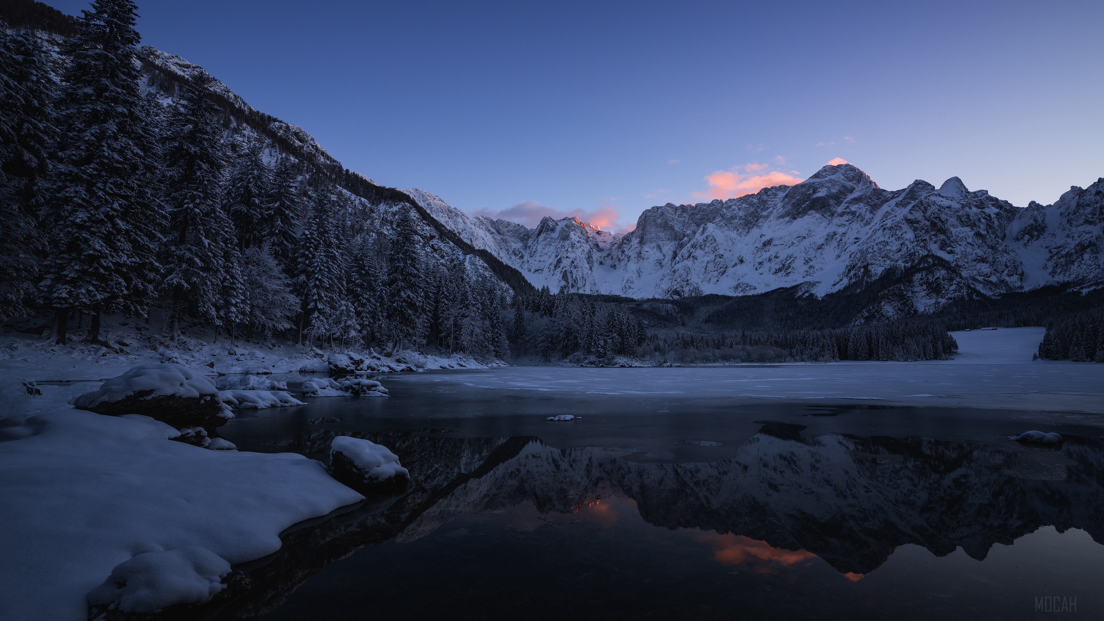 Snowy mountains reflected in a frozen lake at sunrise HD Wallpaper
