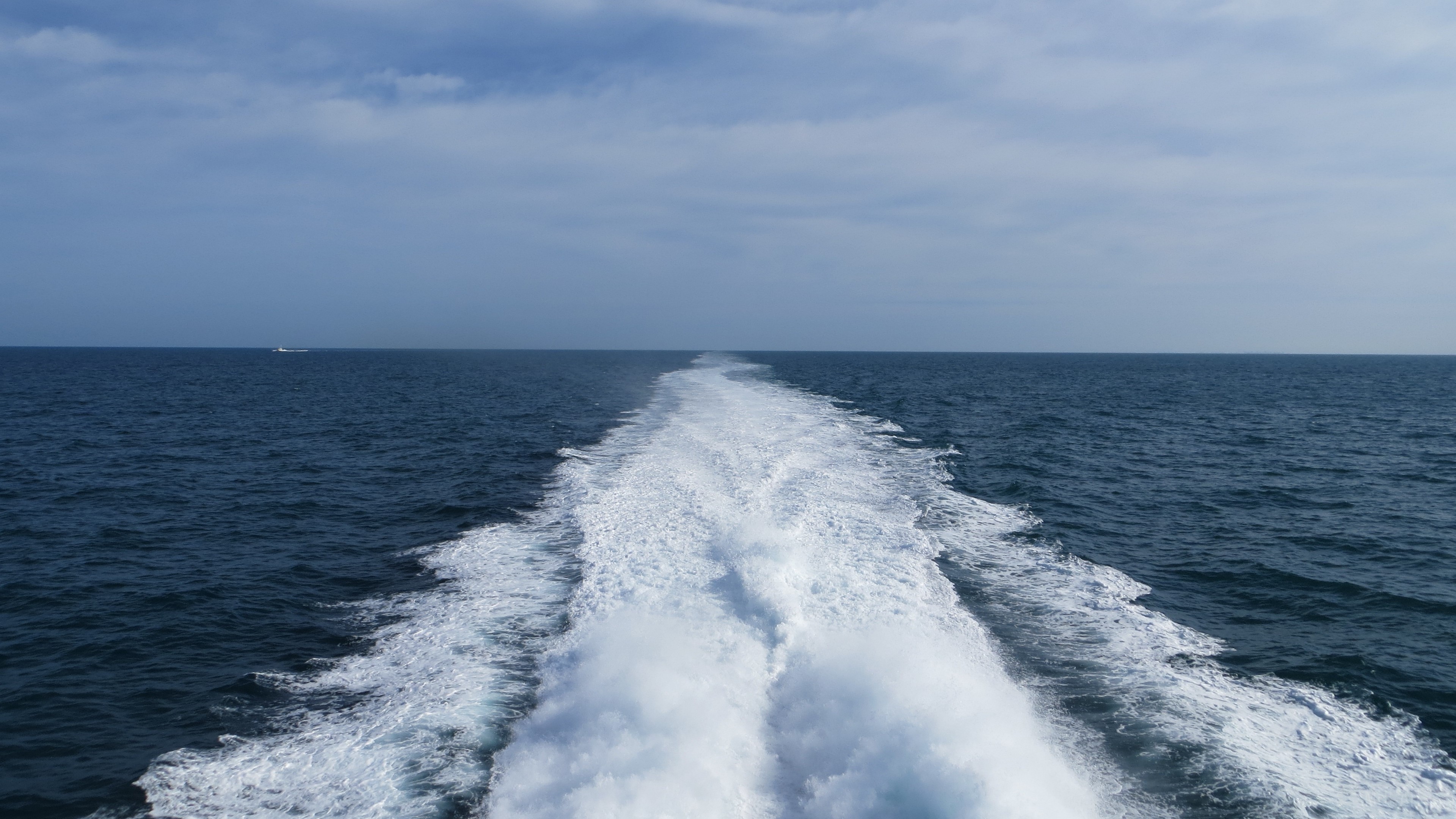 Ocean with boat wake and distant boat HD Wallpaper