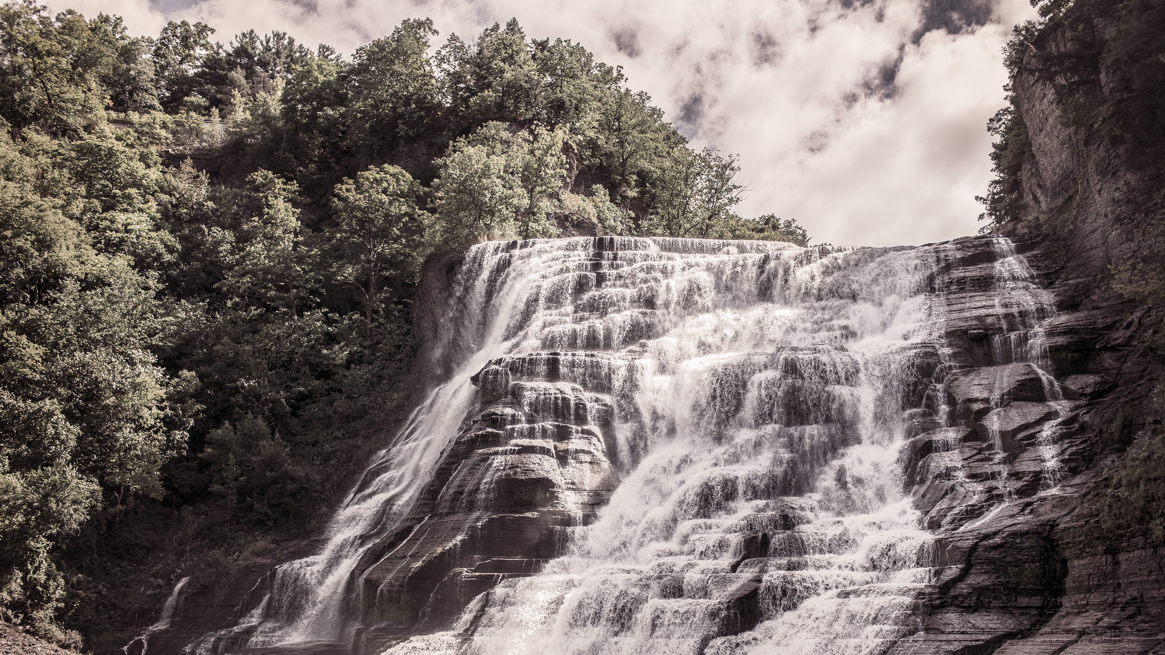 Waterfall cascading down a rocky cliff with trees HD Wallpaper