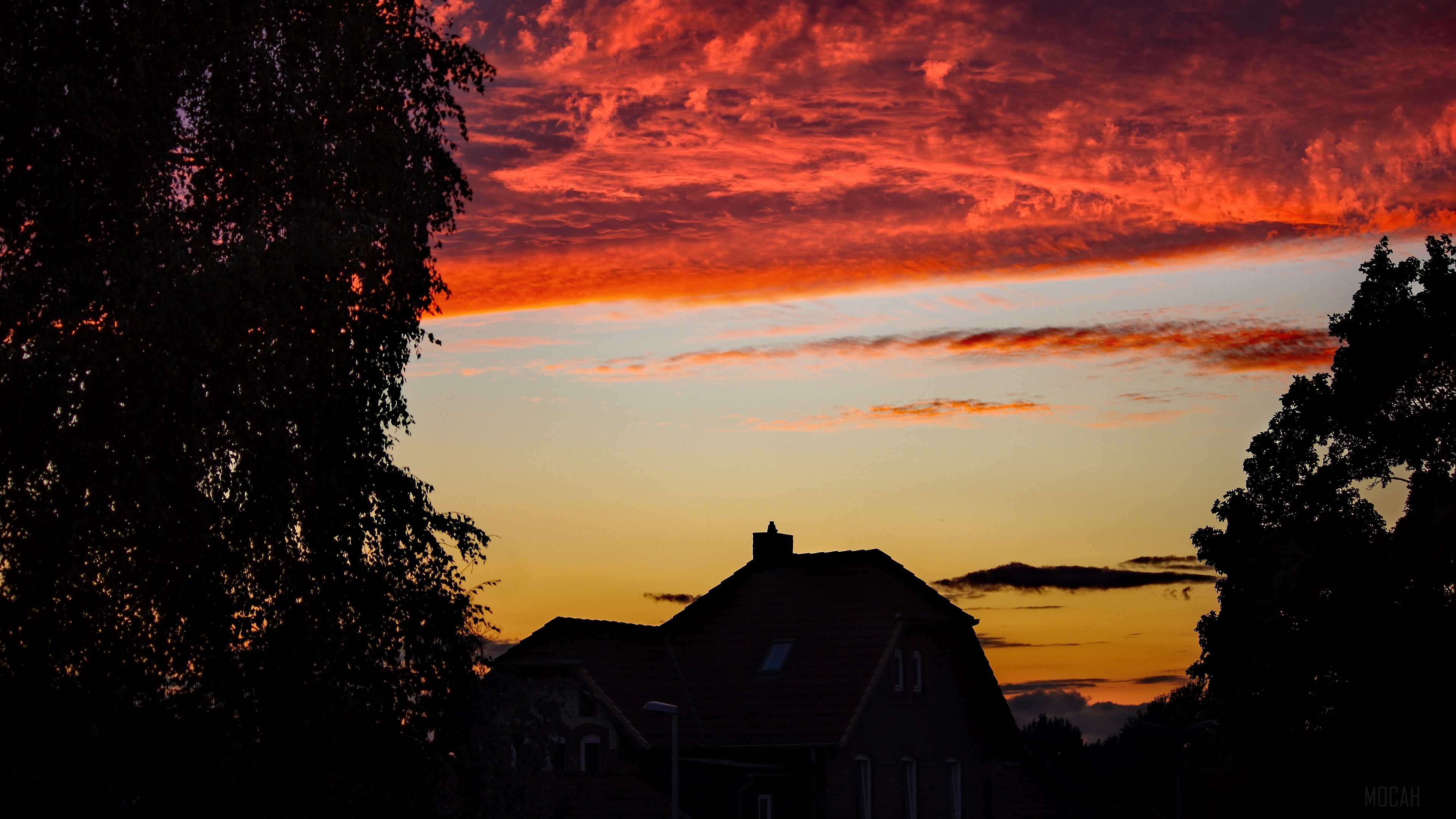 House silhouetted against a dramatic sunset with trees HD Wallpaper