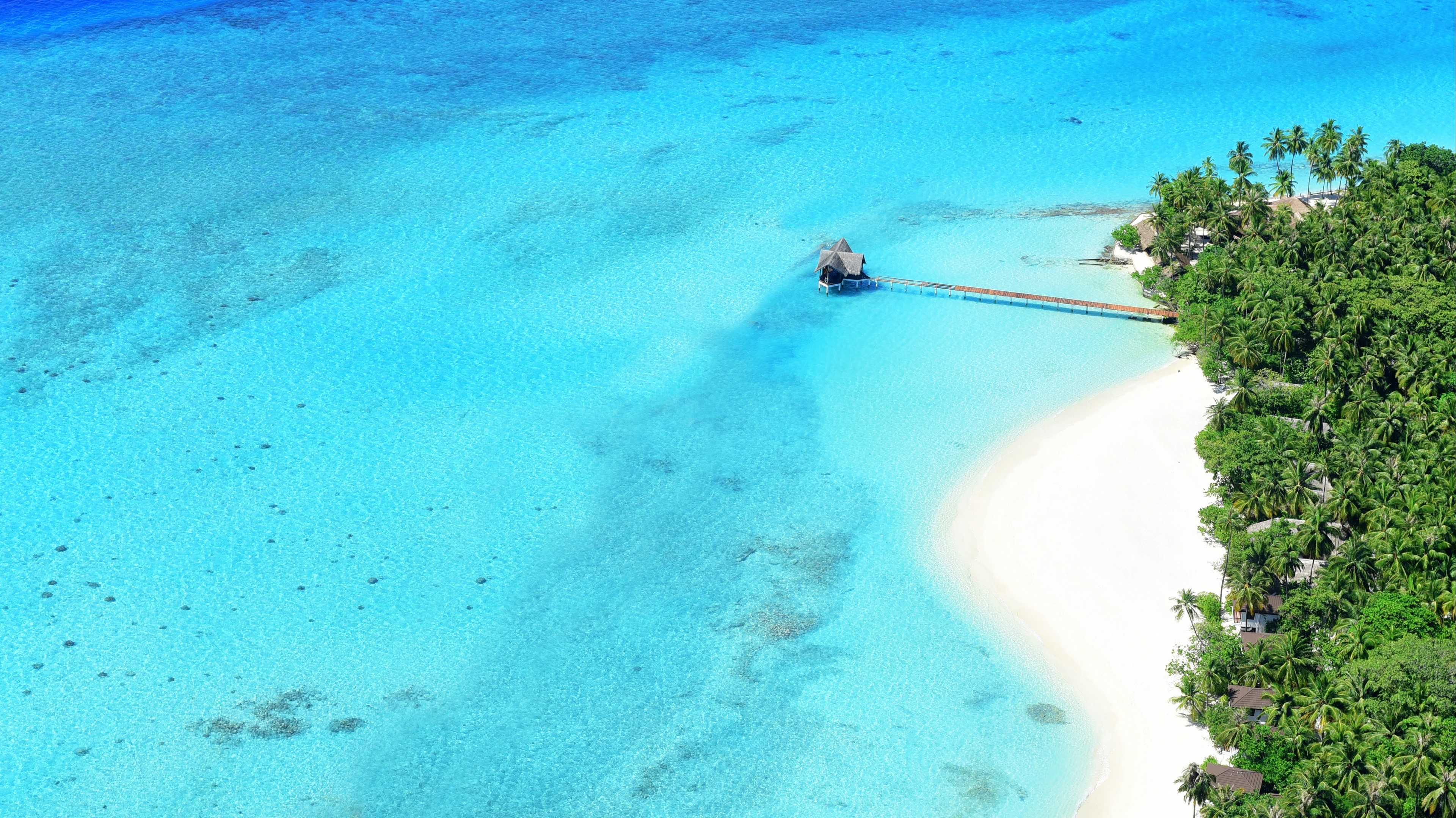 Aerial view of a tropical island resort with overwater bungalows HD Wallpaper