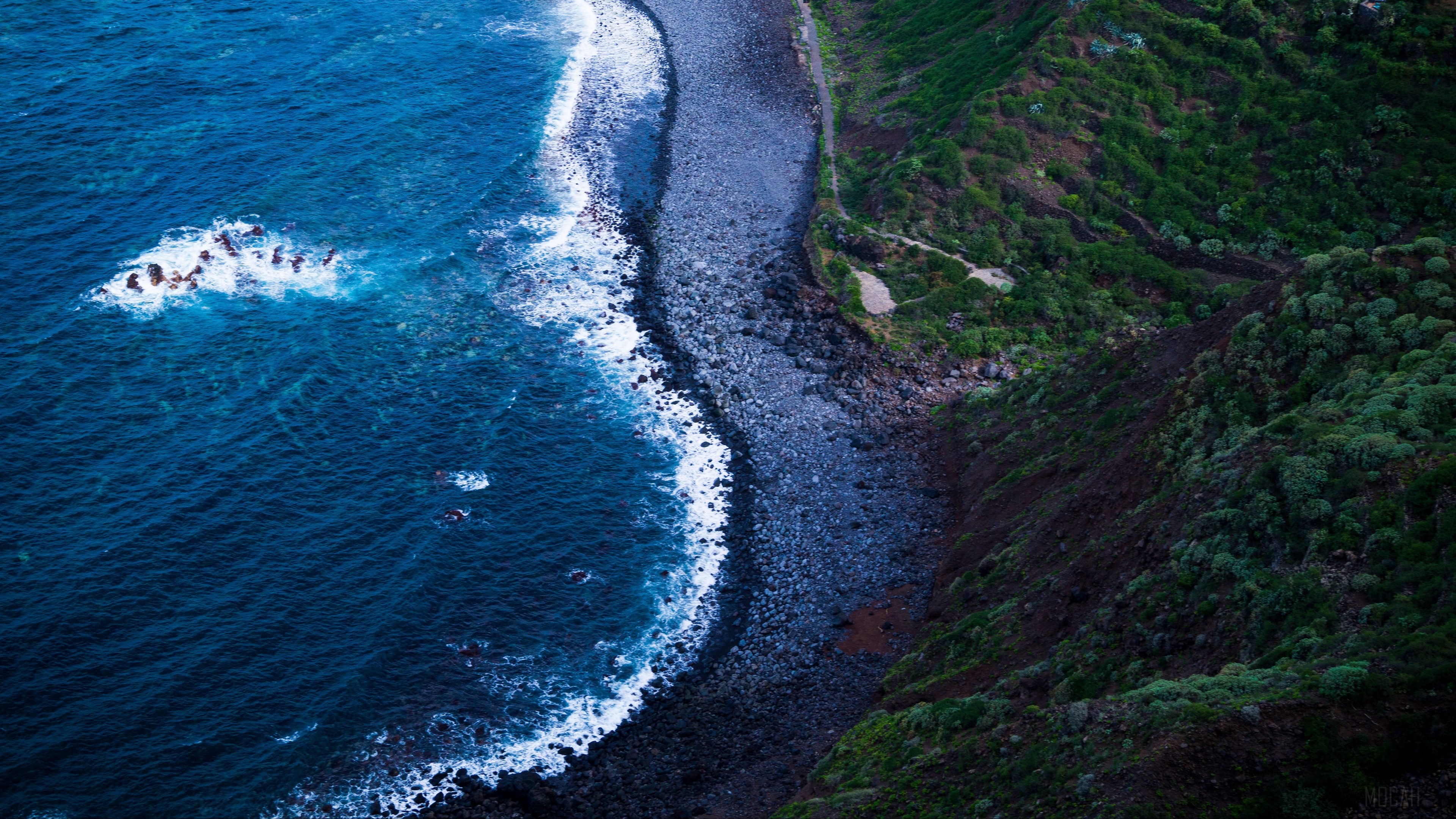 Aerial view of a rocky shore and blue sea HD Wallpaper