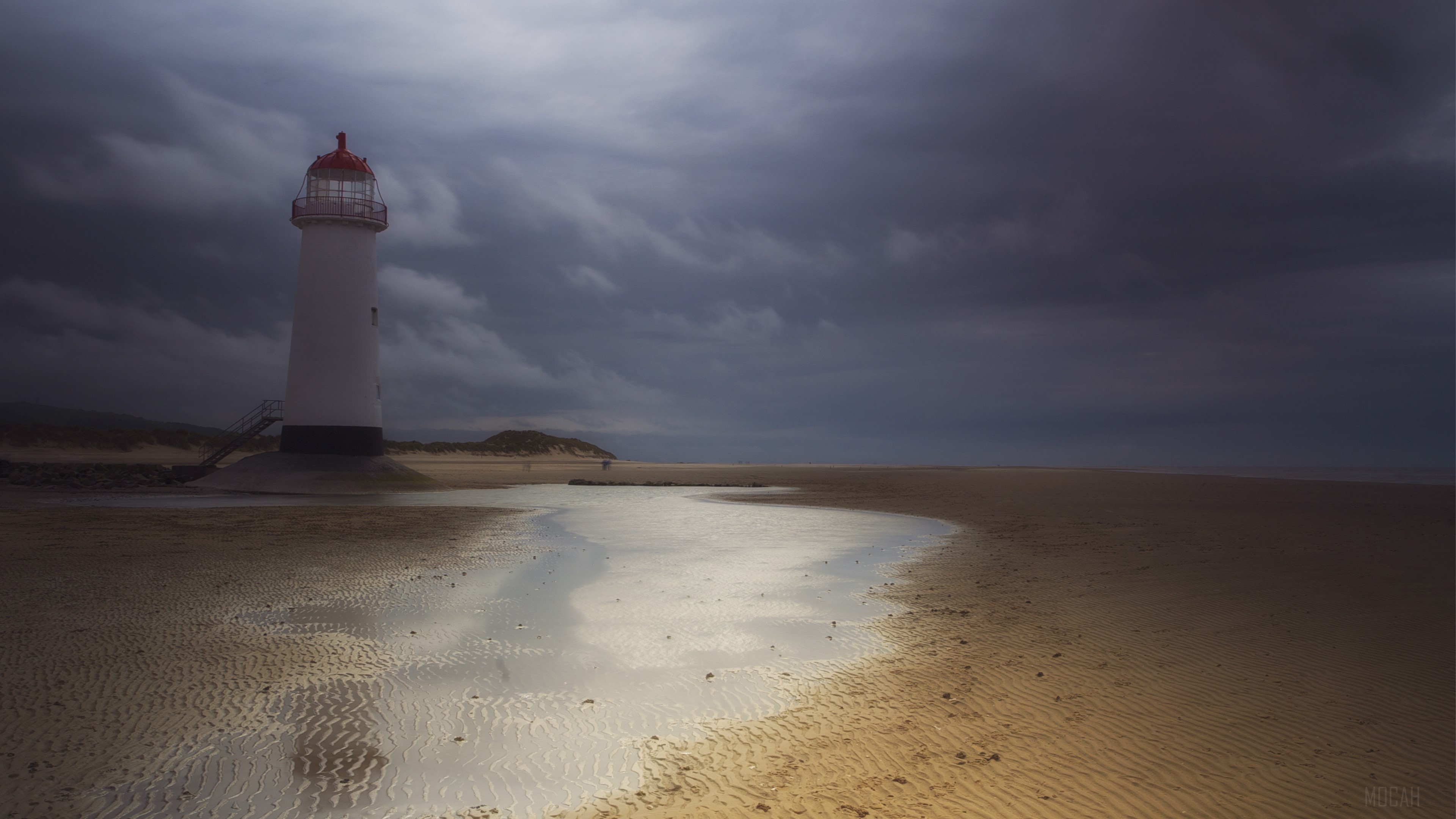 White lighthouse on a sandy beach under cloudy sky 4K HD Wallpaper