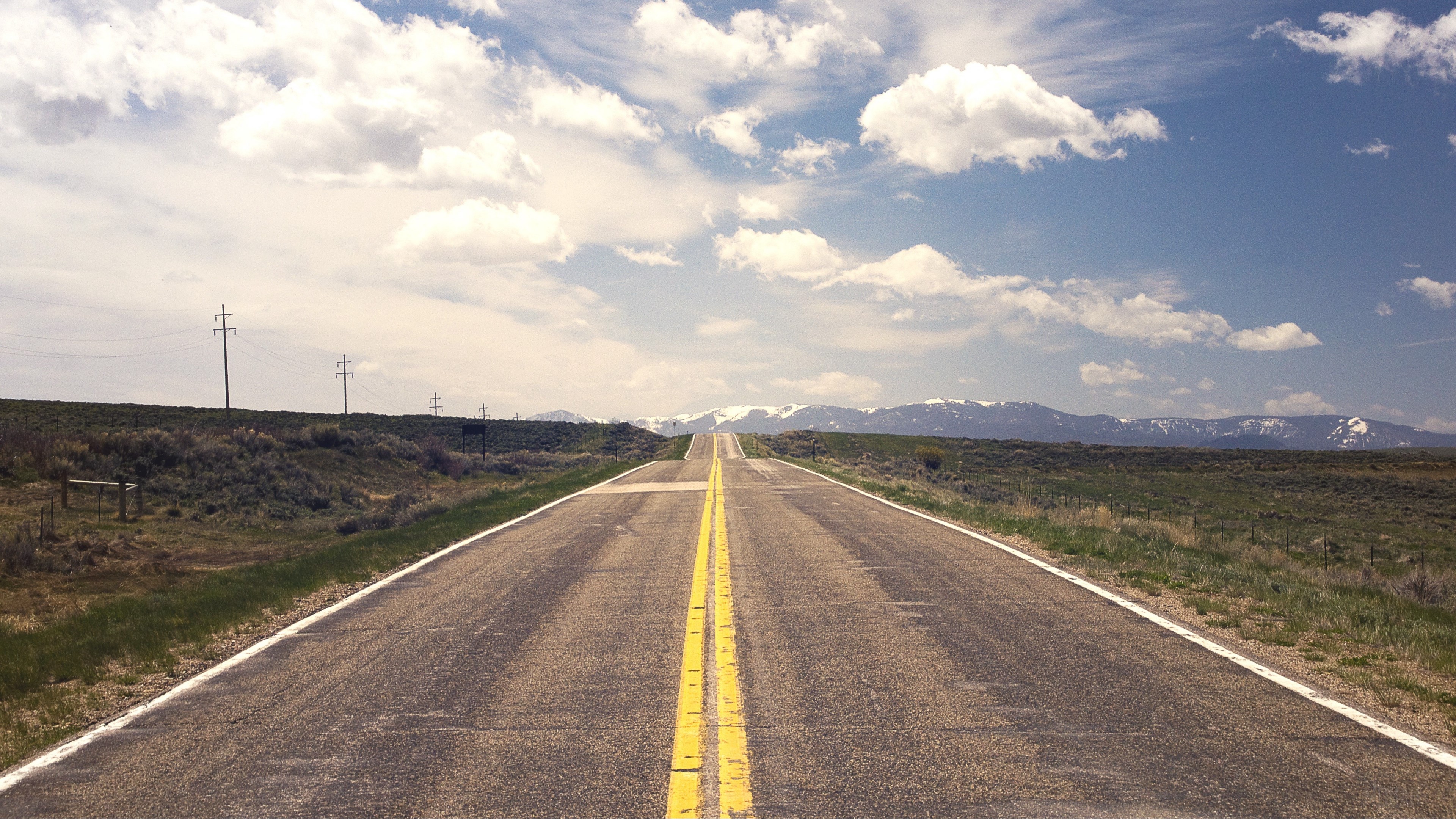 Road stretching to snow-capped mountains HD Wallpaper