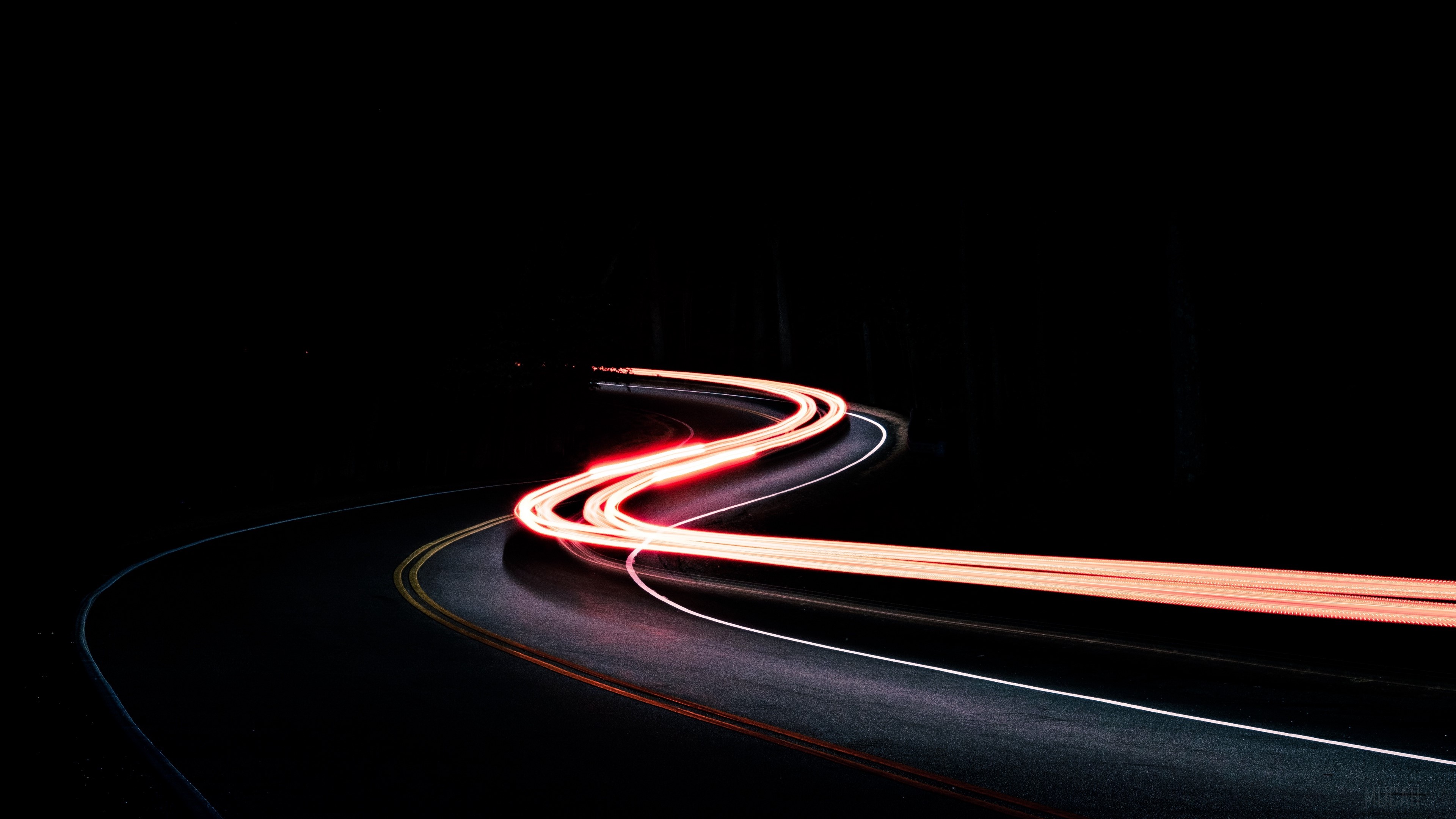Light trails on a winding road at night HD Wallpaper