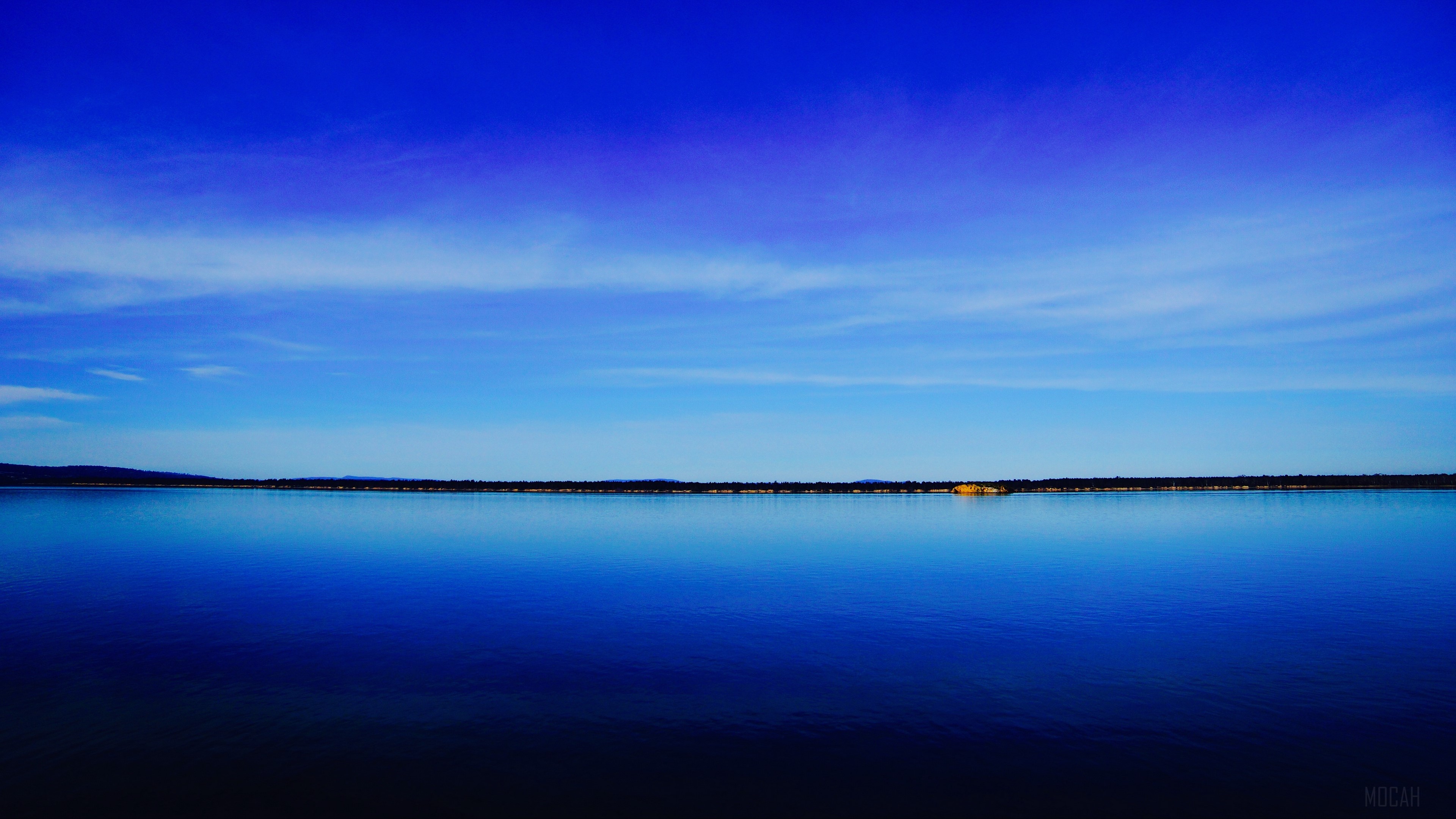 Vast blue lake under a clear sky HD Wallpaper