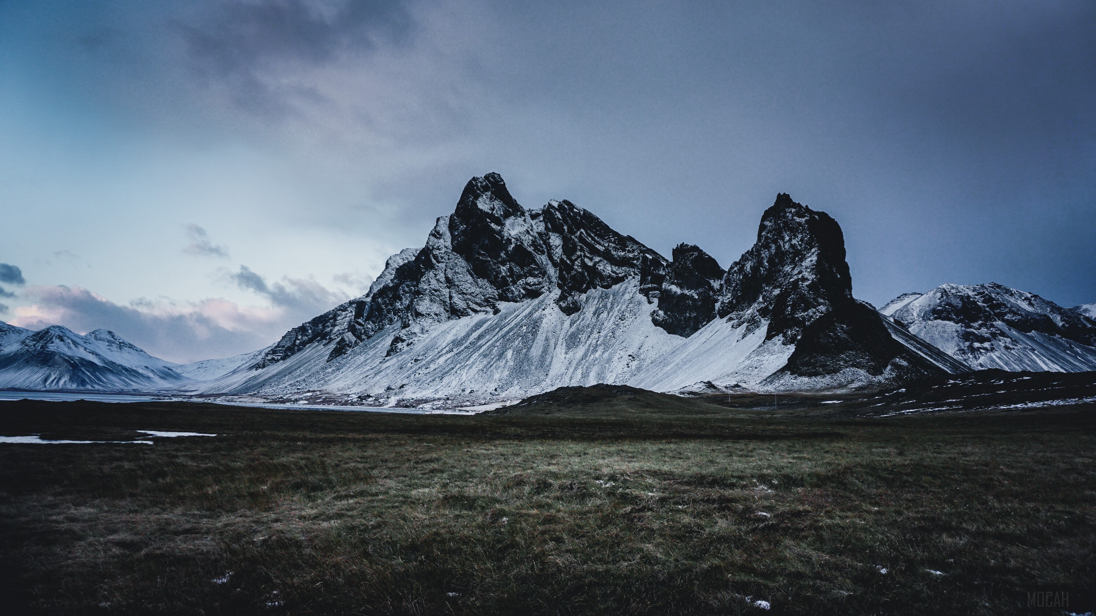 Snow-covered mountains and grassy field at dusk HD Wallpaper