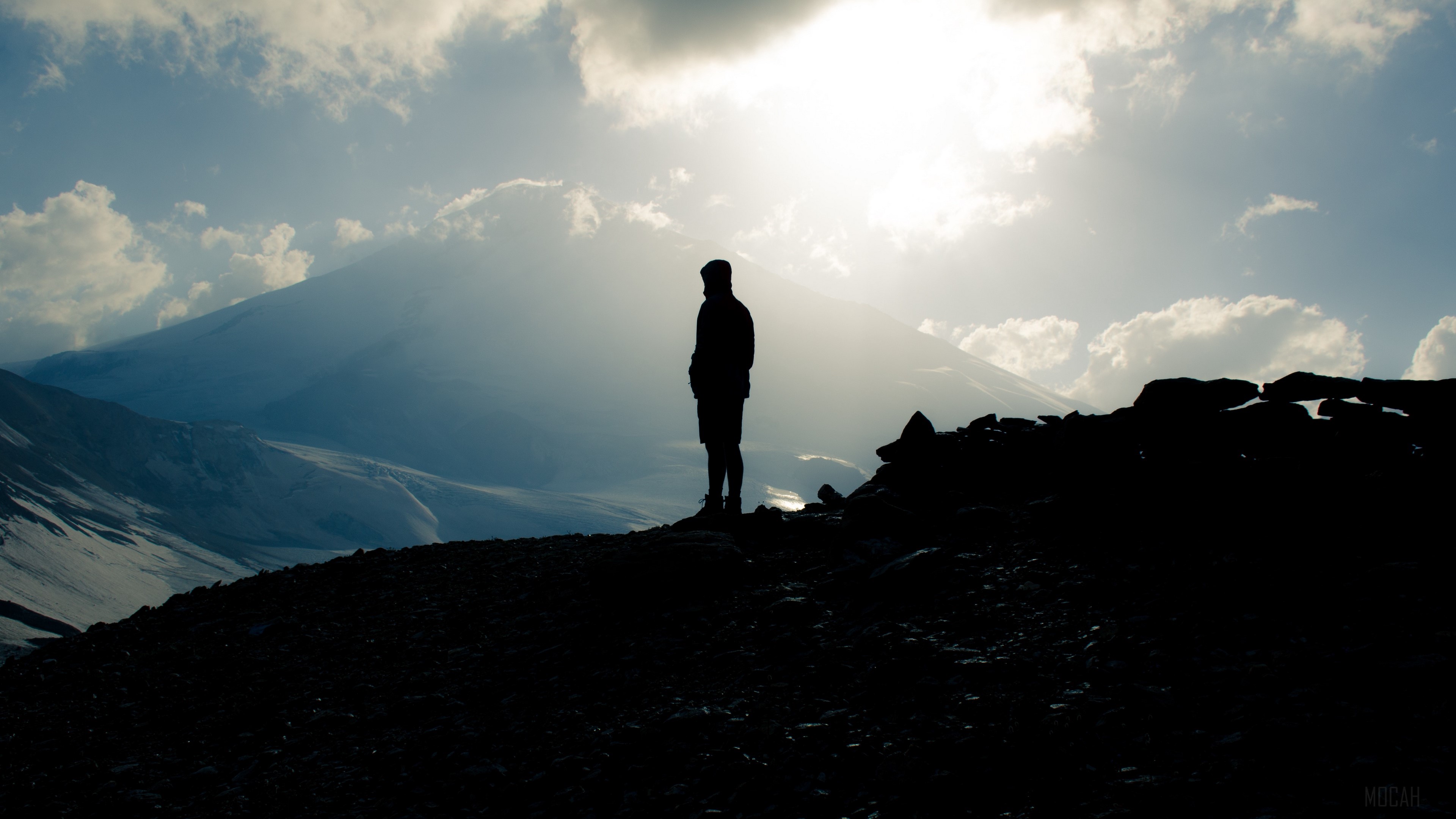 Silhouette of a person on a mountain with Mount Elbrus in the background HD Wallpaper