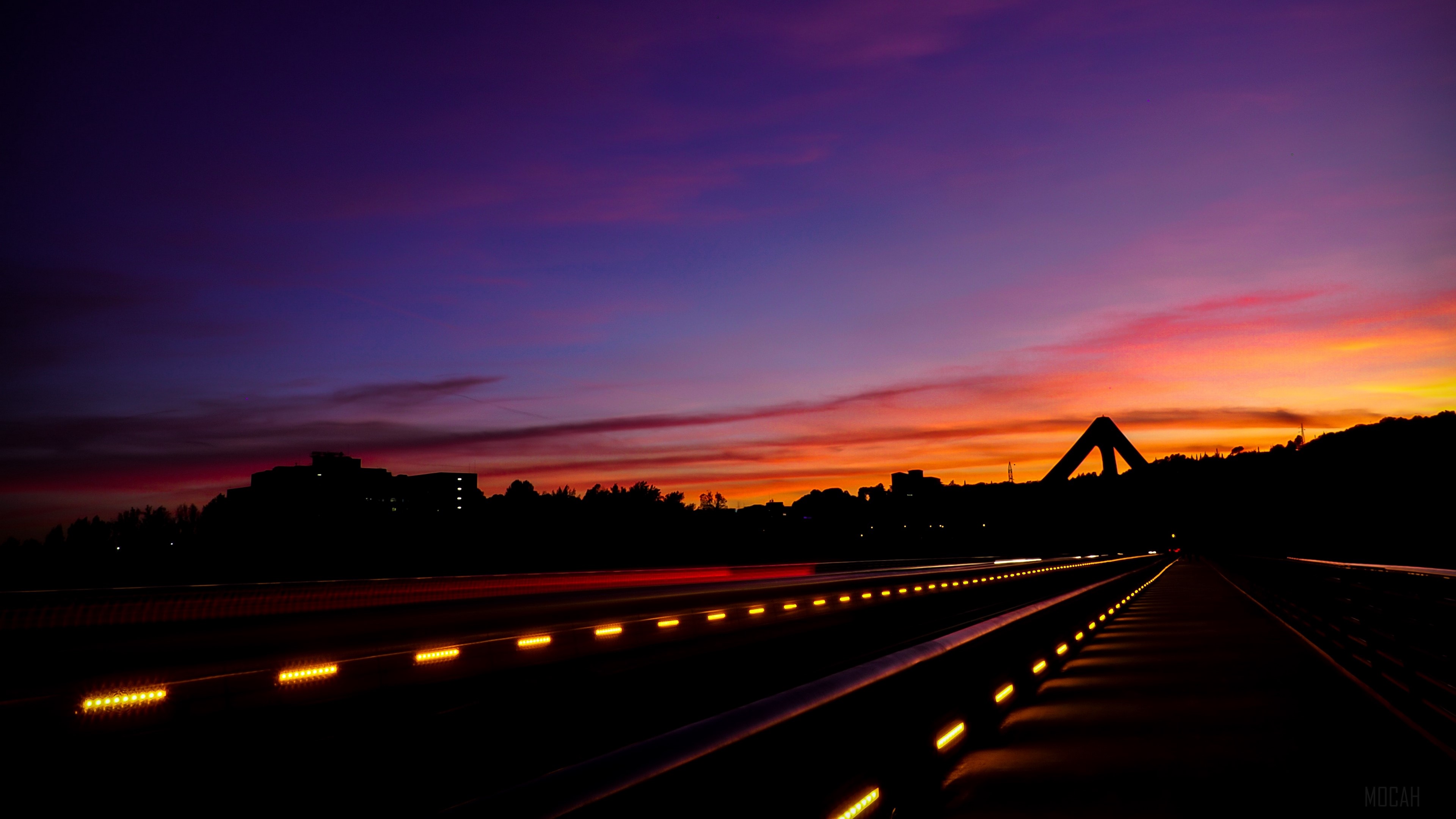 Road markings at sunset with a bridge silhouette HD Wallpaper