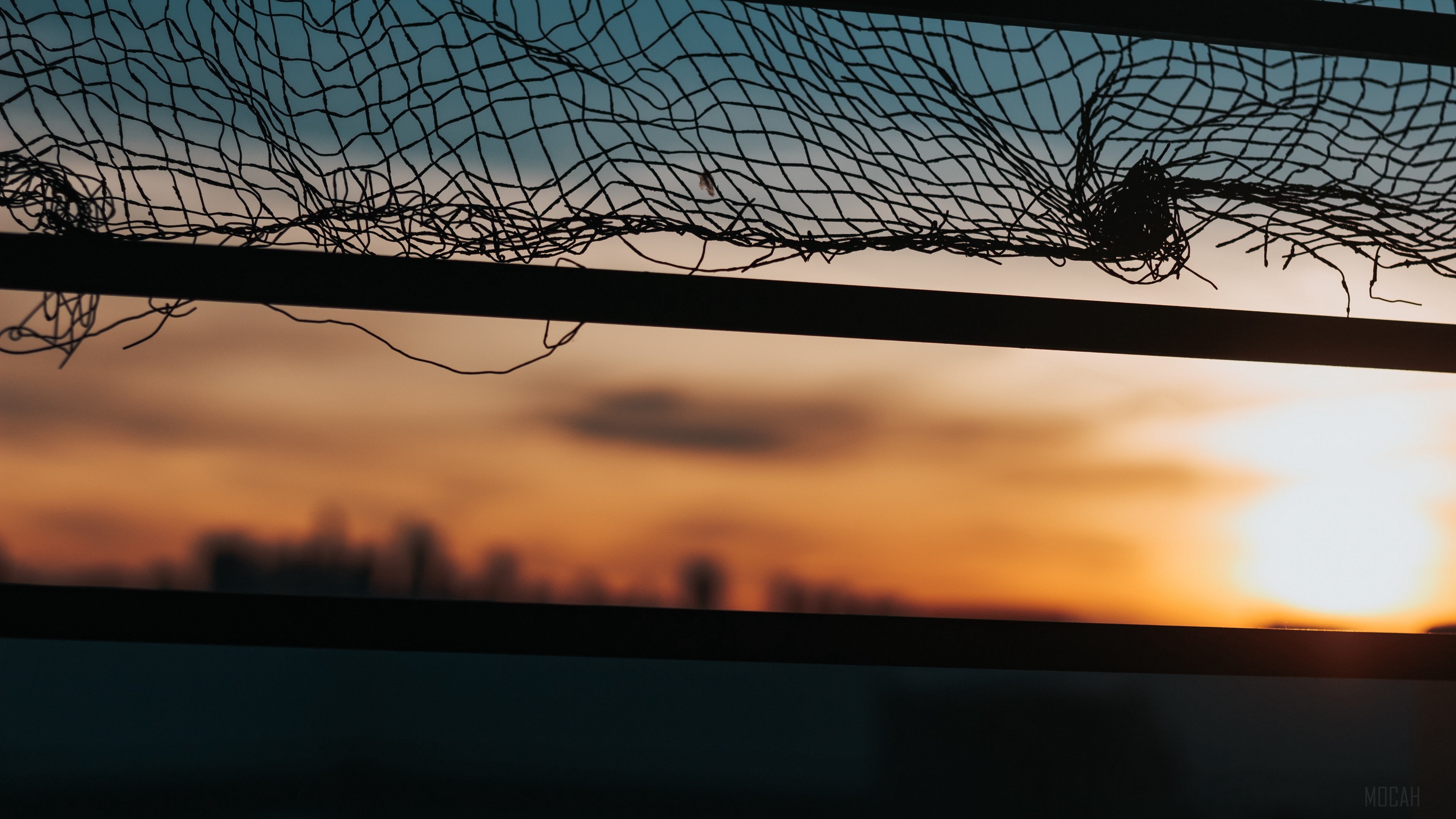 Torn mesh against sunset sky with city skyline HD Wallpaper