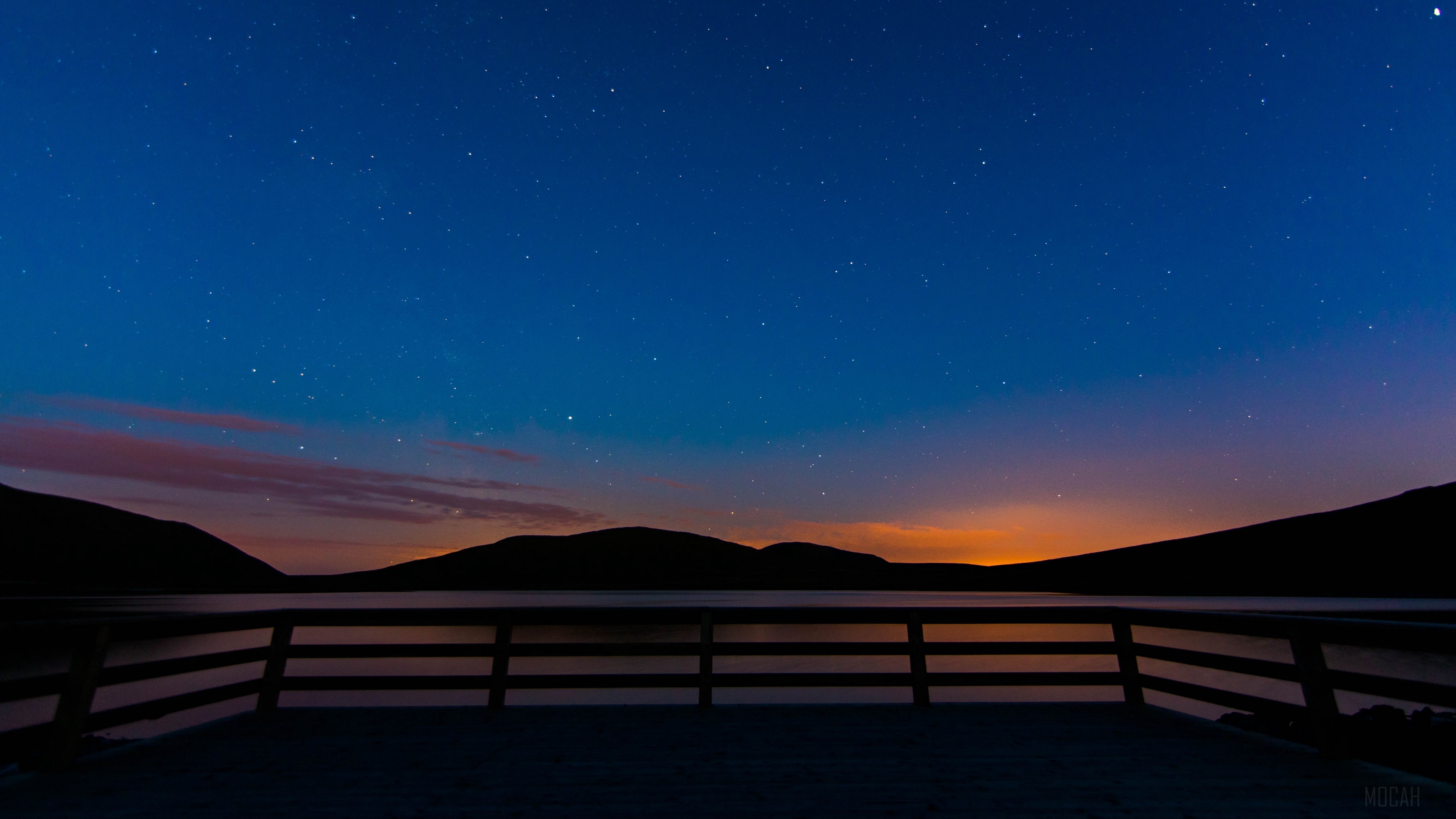 Starry sky over mountains and lake with railing HD Wallpaper