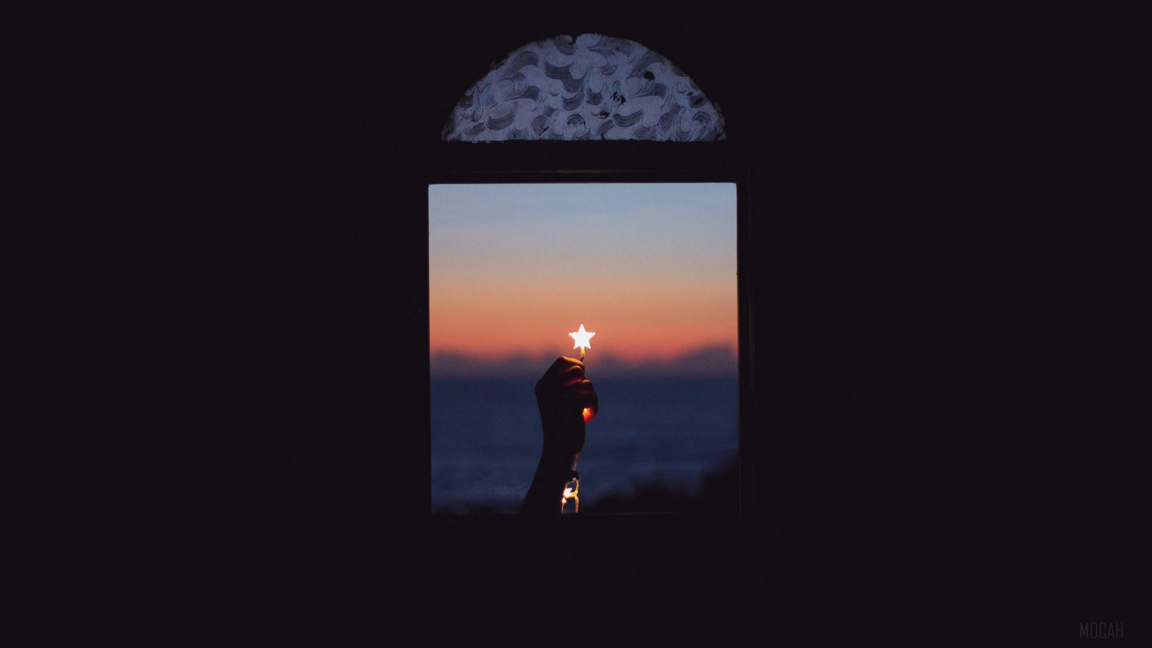 Hand holding a star sparkler through a window at sunset HD Wallpaper