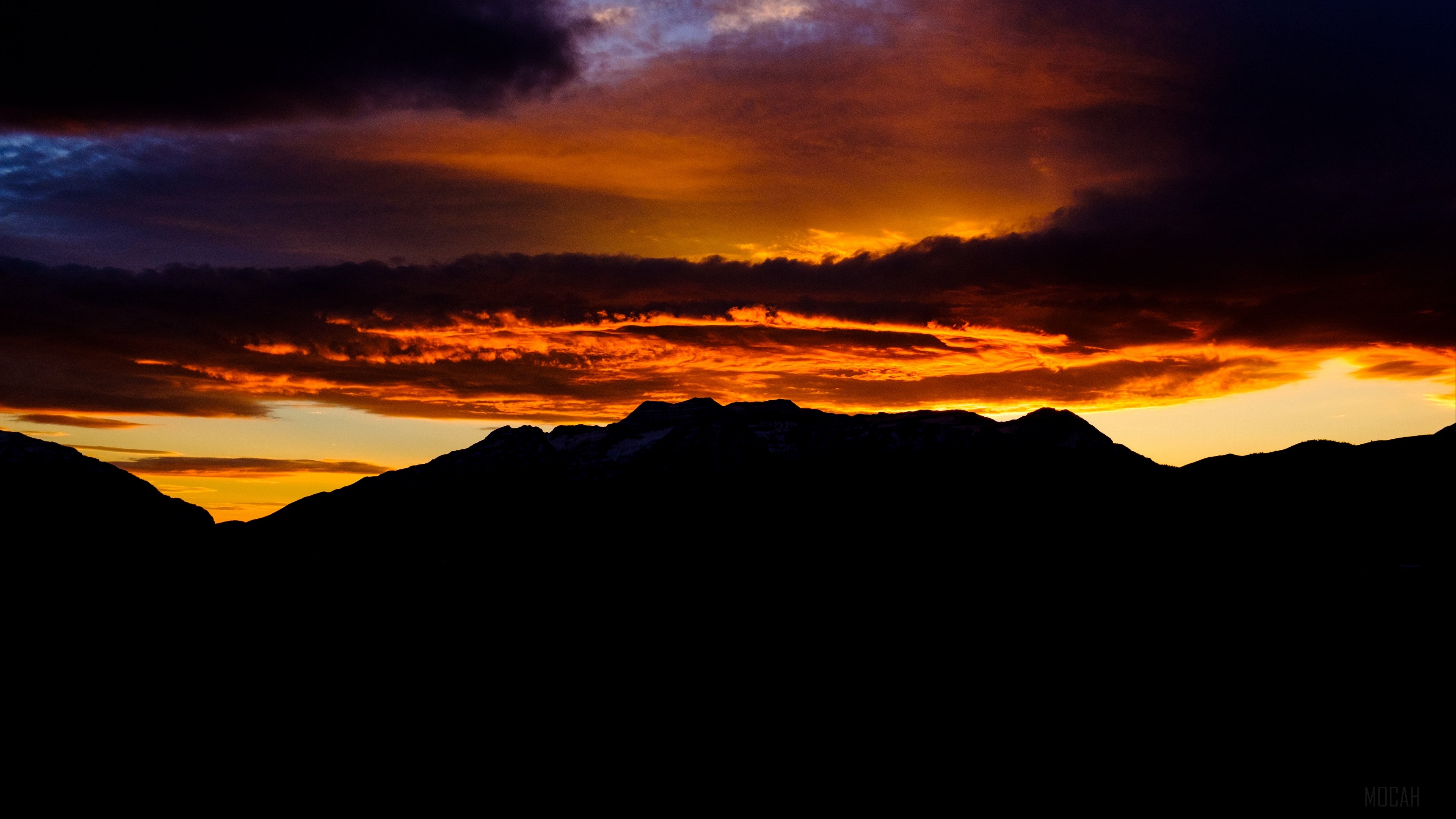 Dark mountains silhouette against a vibrant sunset sky with clouds 4K HD Wallpaper