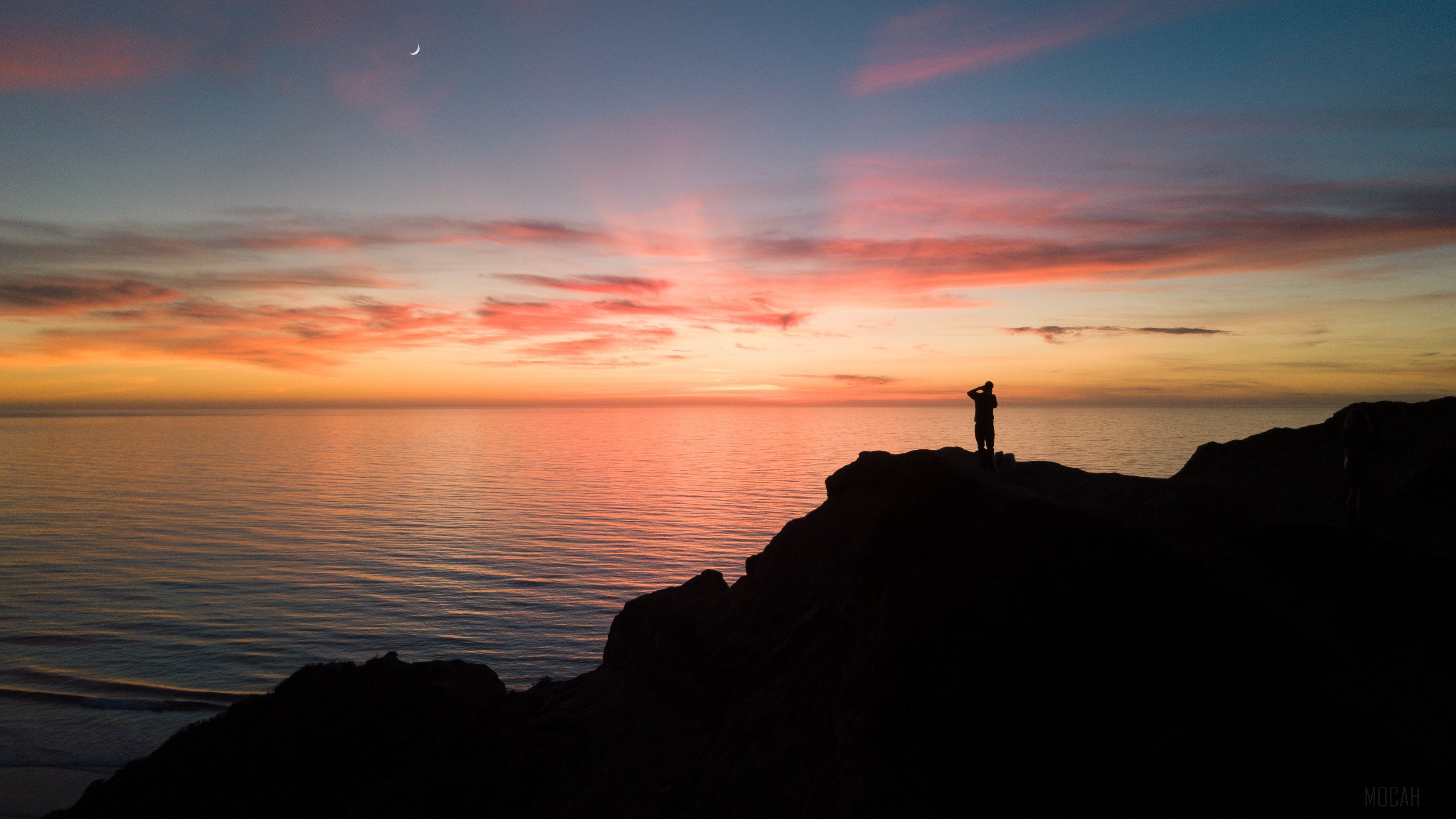 Silhouette of a person on a cliff overlooking the sea at sunset 4K HD Wallpaper