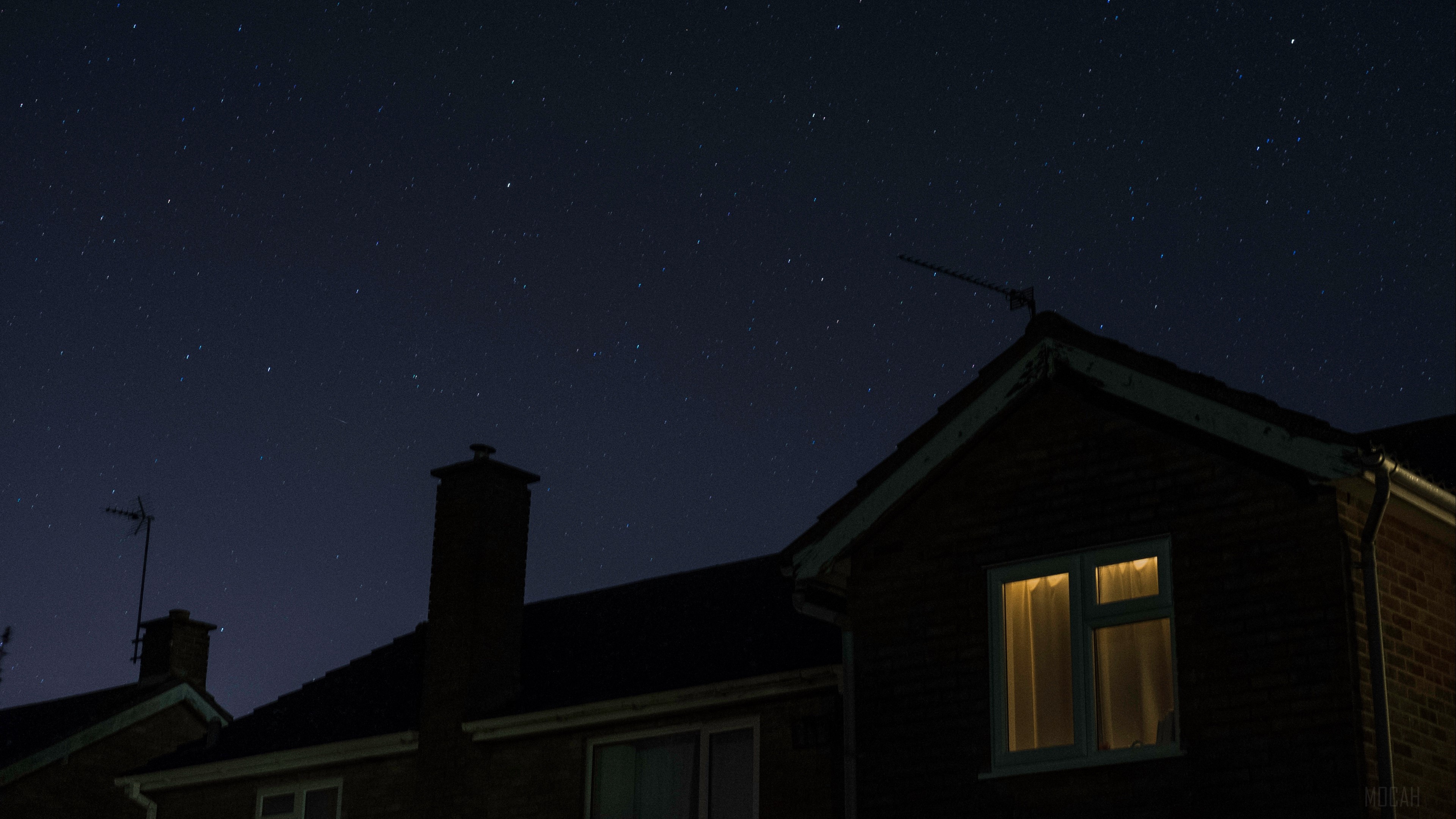 Starry night sky over houses with lit window HD Wallpaper