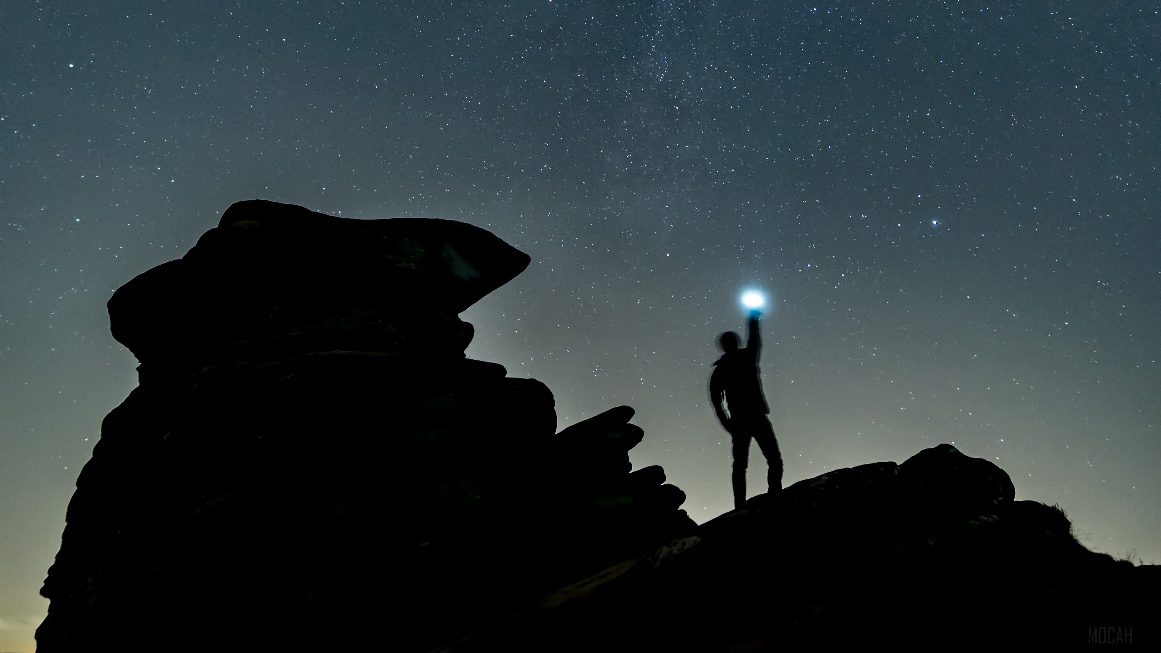 Silhouette of a person holding a light under a starry sky HD Wallpaper