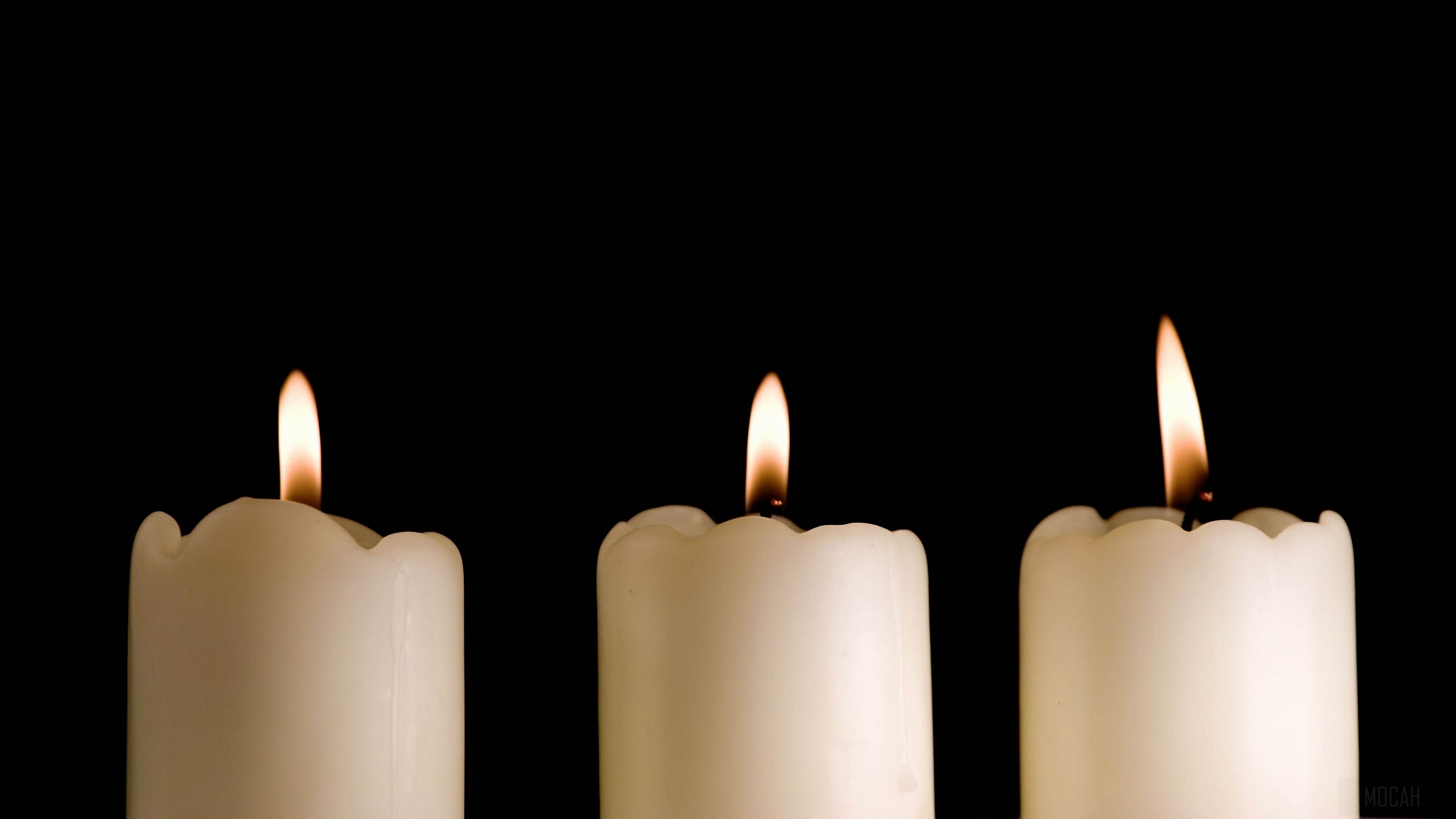 Three lit candles on a black background 4K HD Wallpaper