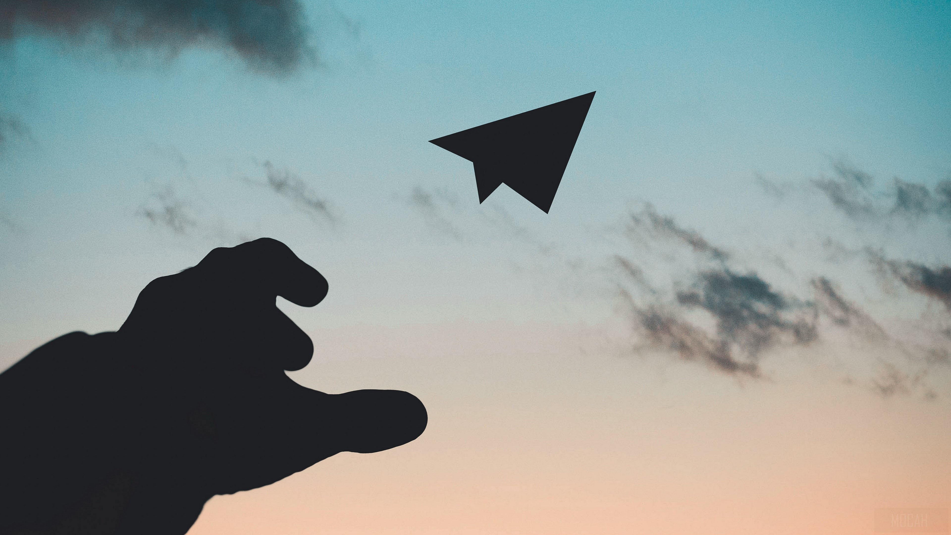 Silhouette of a hand throwing a paper airplane against a sunset sky HD Wallpaper