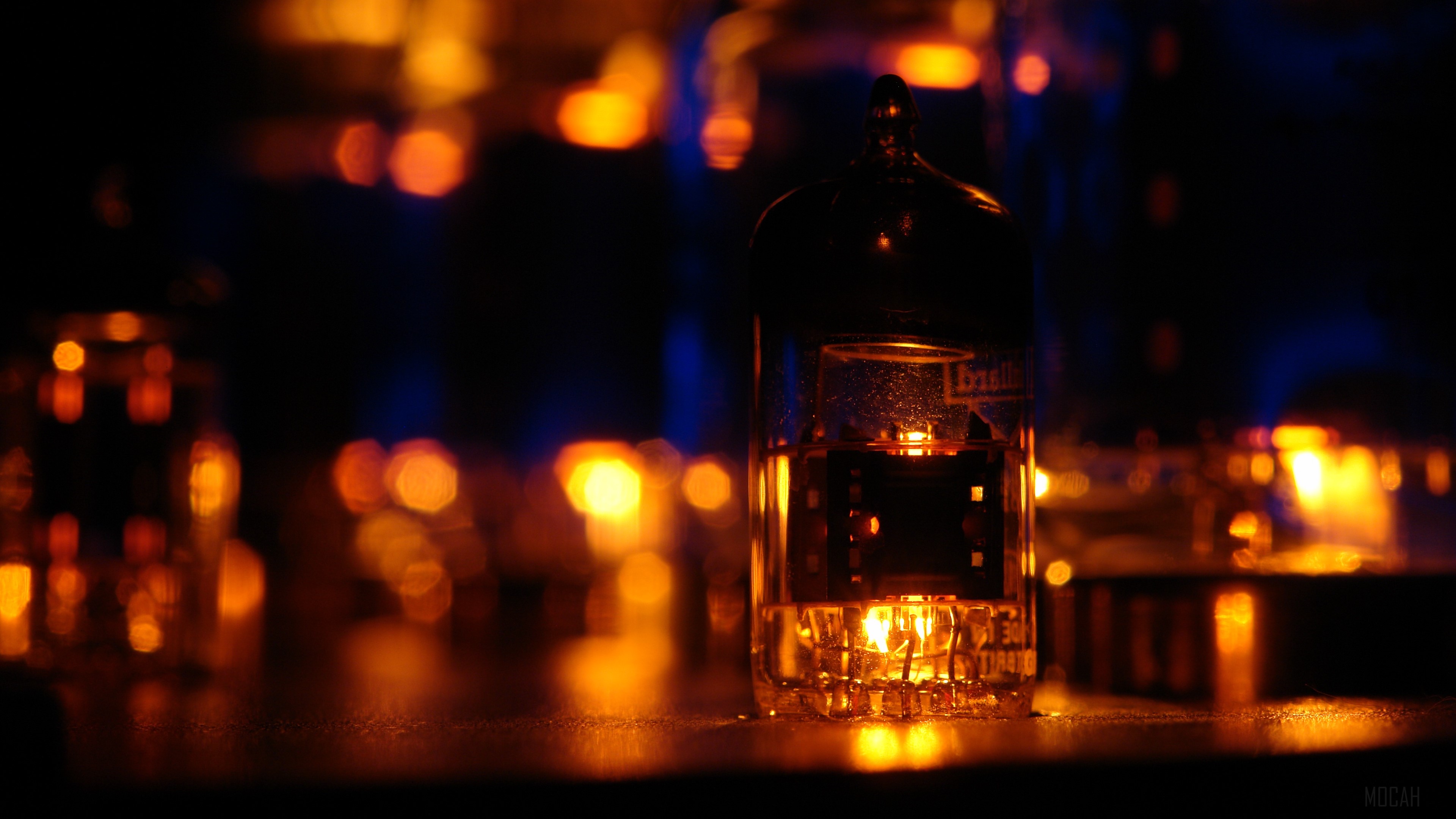 Vacuum tube with glowing filament and bokeh lights 4K HD Wallpaper