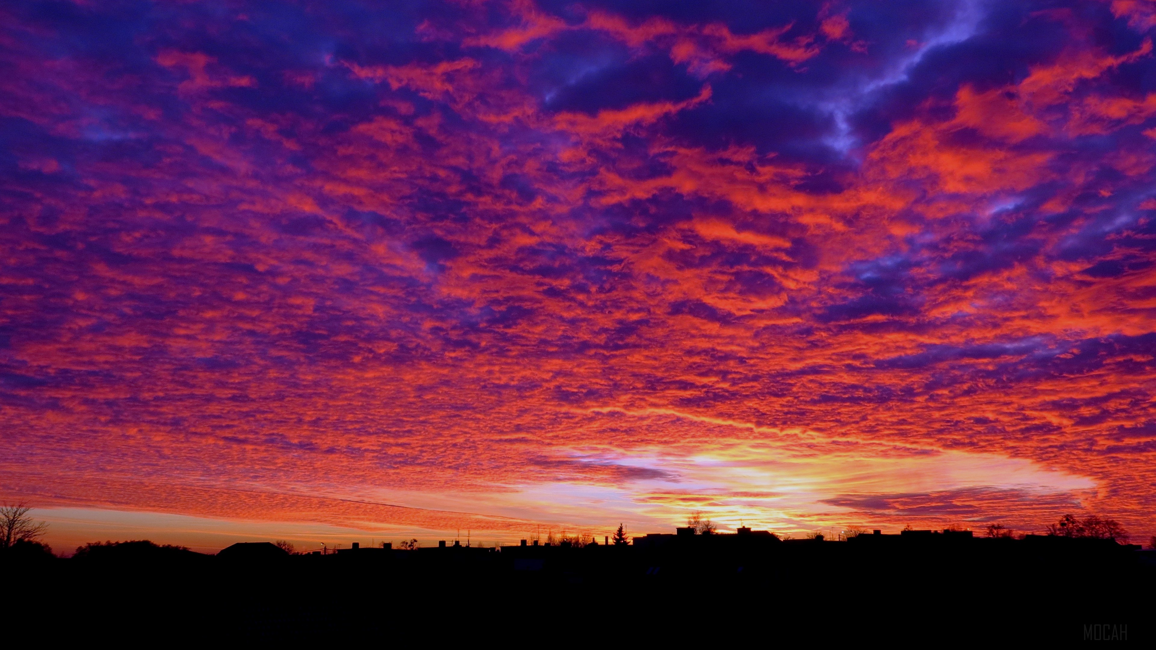 Sunset clouds over a silhouetted horizon HD Wallpaper
