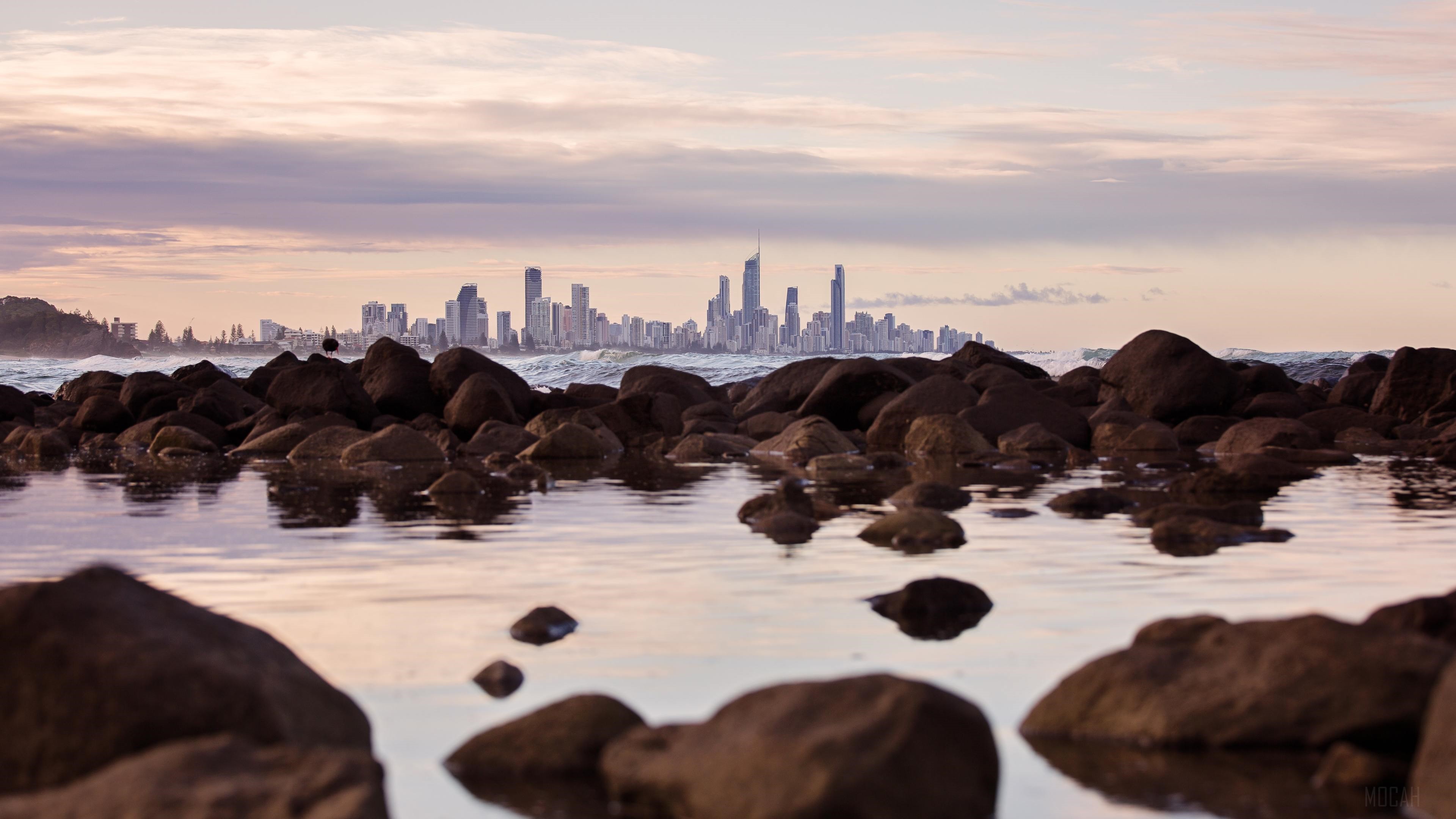 Seashore Rocks With City Skyline View 4K HD Wallpaper