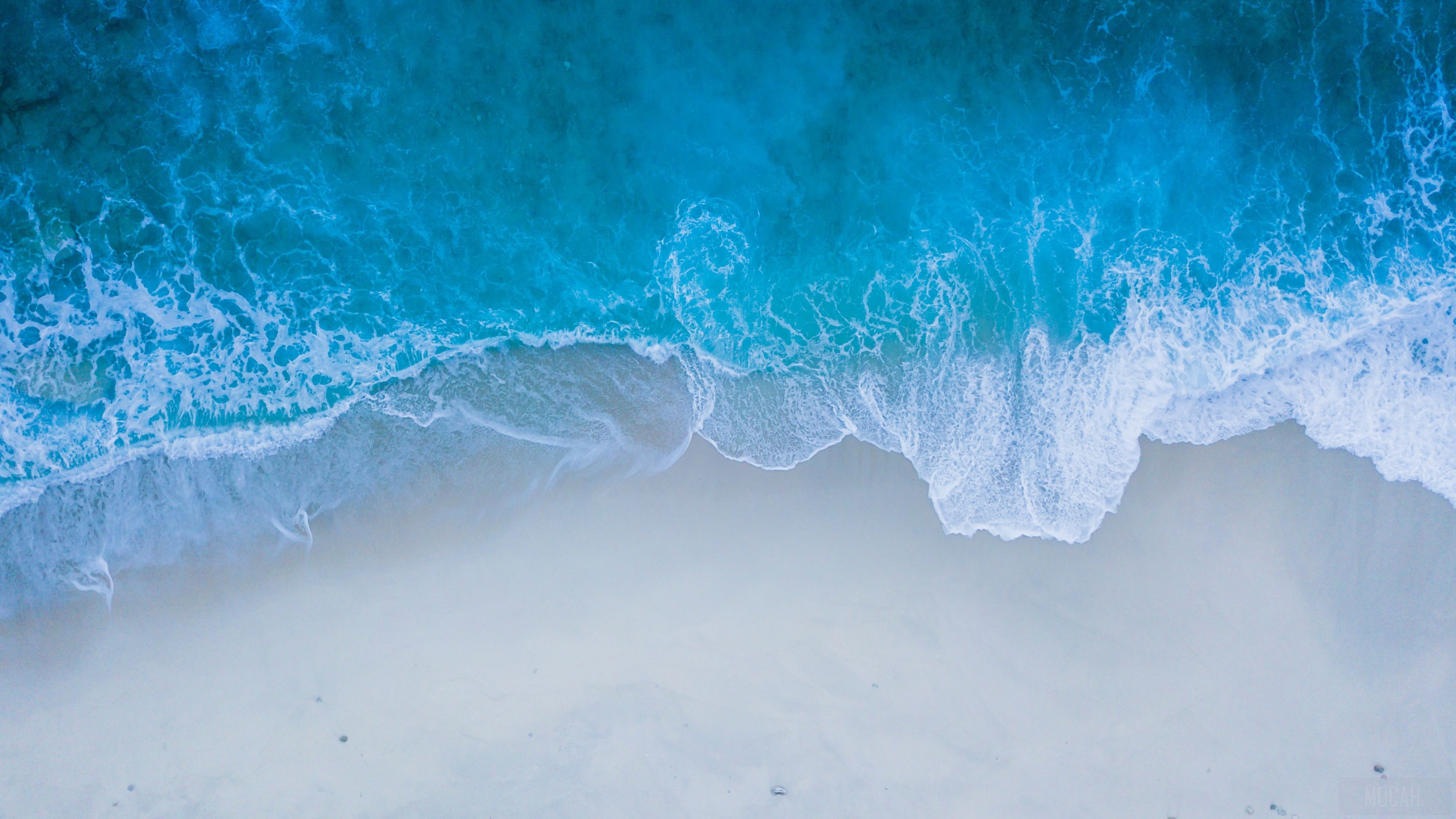 Aerial view of ocean waves crashing on a sandy beach HD Wallpaper